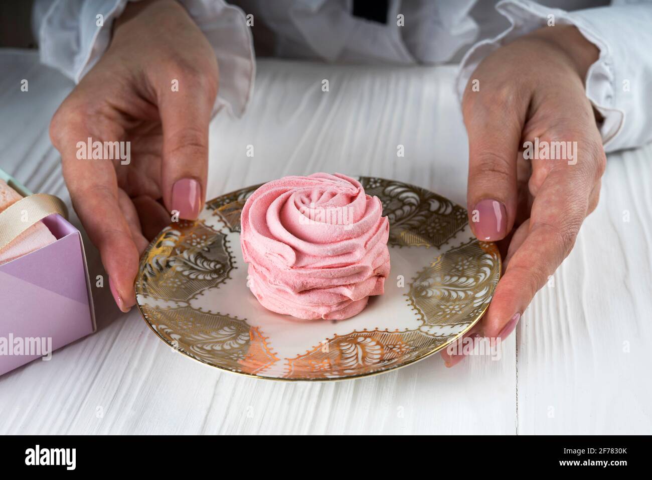 Mani femminili e piattino con marshmallow rosa Foto Stock