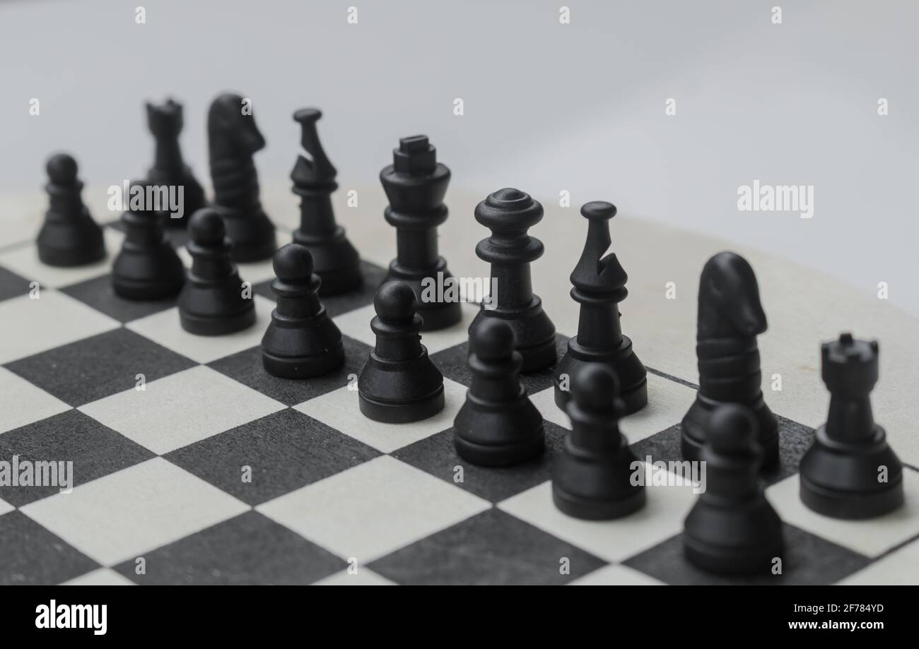 Pezzi di scacchi in plastica nera su tavola di legno naturale, Chessboard fuoco selettivo di pedine e gioco di scacchi impostato Foto Stock