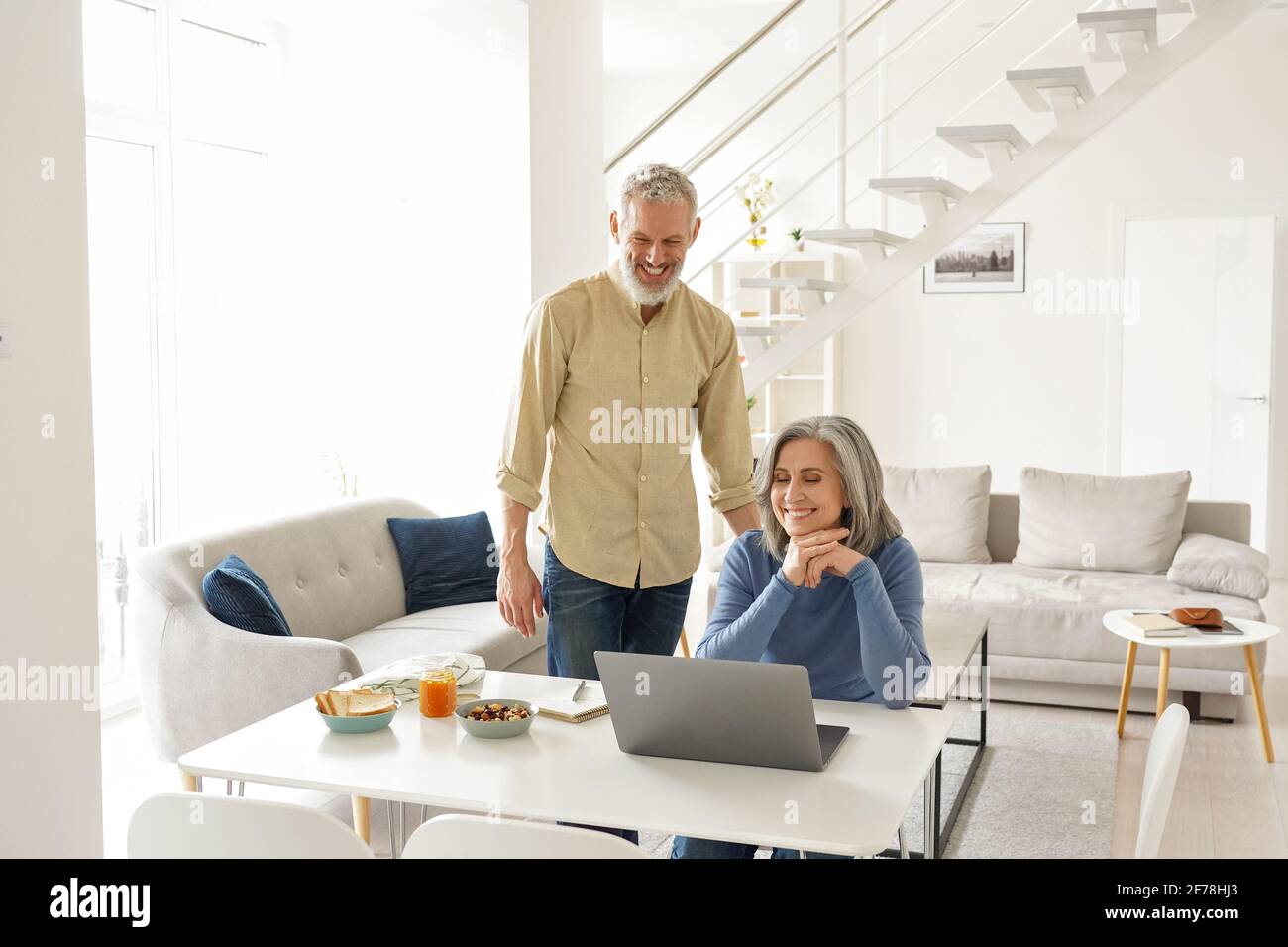Felice coppia senior matura che ha una riunione virtuale sul computer portatile a casa. Foto Stock
