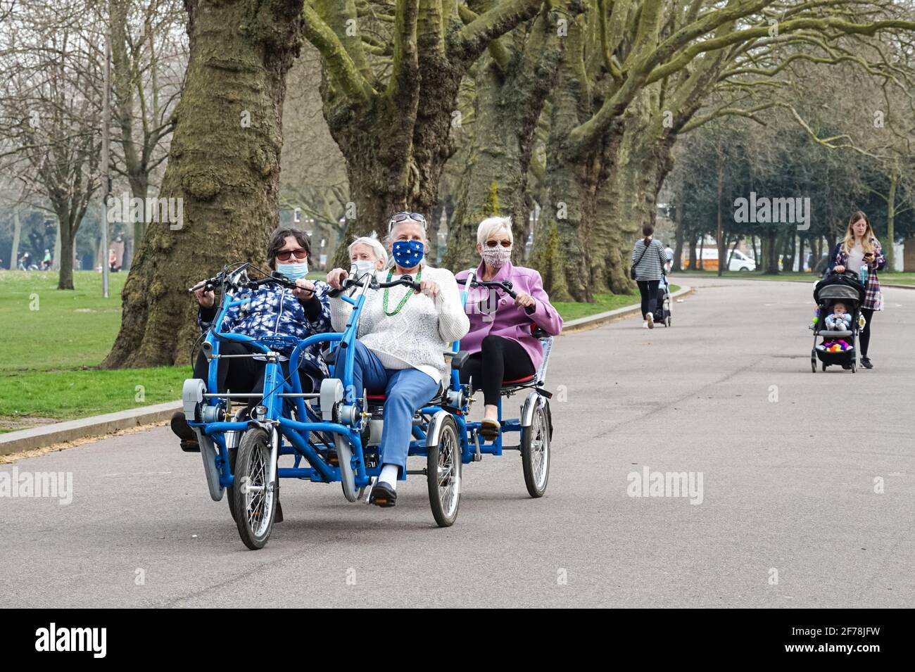 Donne anziane che indossano maschere facciali e cavalcano un quadriciclo in un parco durante l'epidemia di coronavirus a Londra, Inghilterra Regno Unito Foto Stock