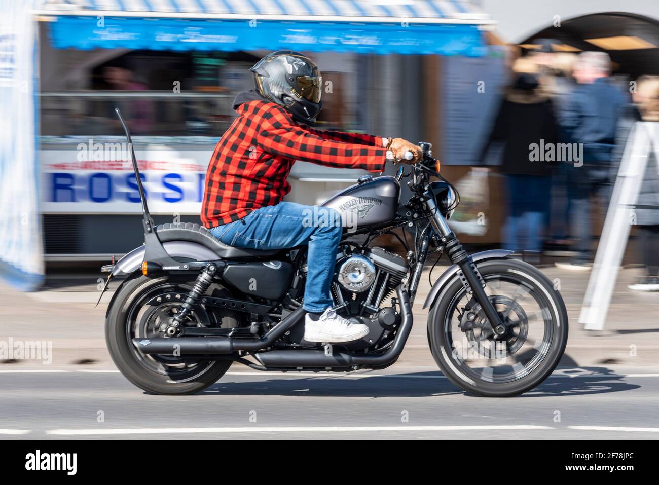 Harley Davidson motociclista, a Southend on Sea, Essex, Regno Unito. Motore S&S Super. Cavaliere che indossa una camicia in plaid e jeans in denim blu. Giorno di sole Foto Stock