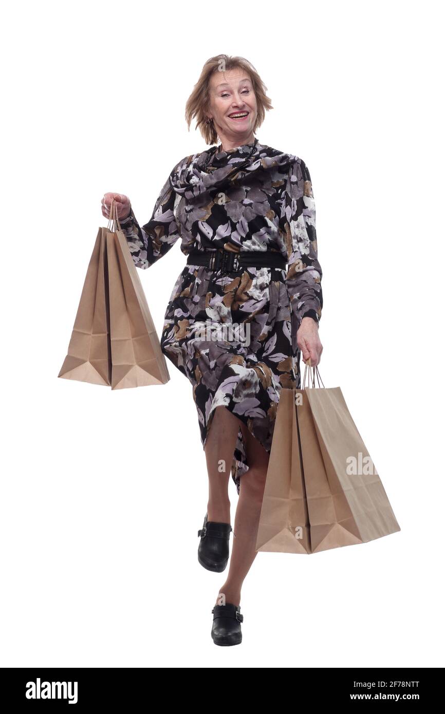 Donna caucasica anziana che cammina con borse per lo shopping sorridente al telespettatore Foto Stock
