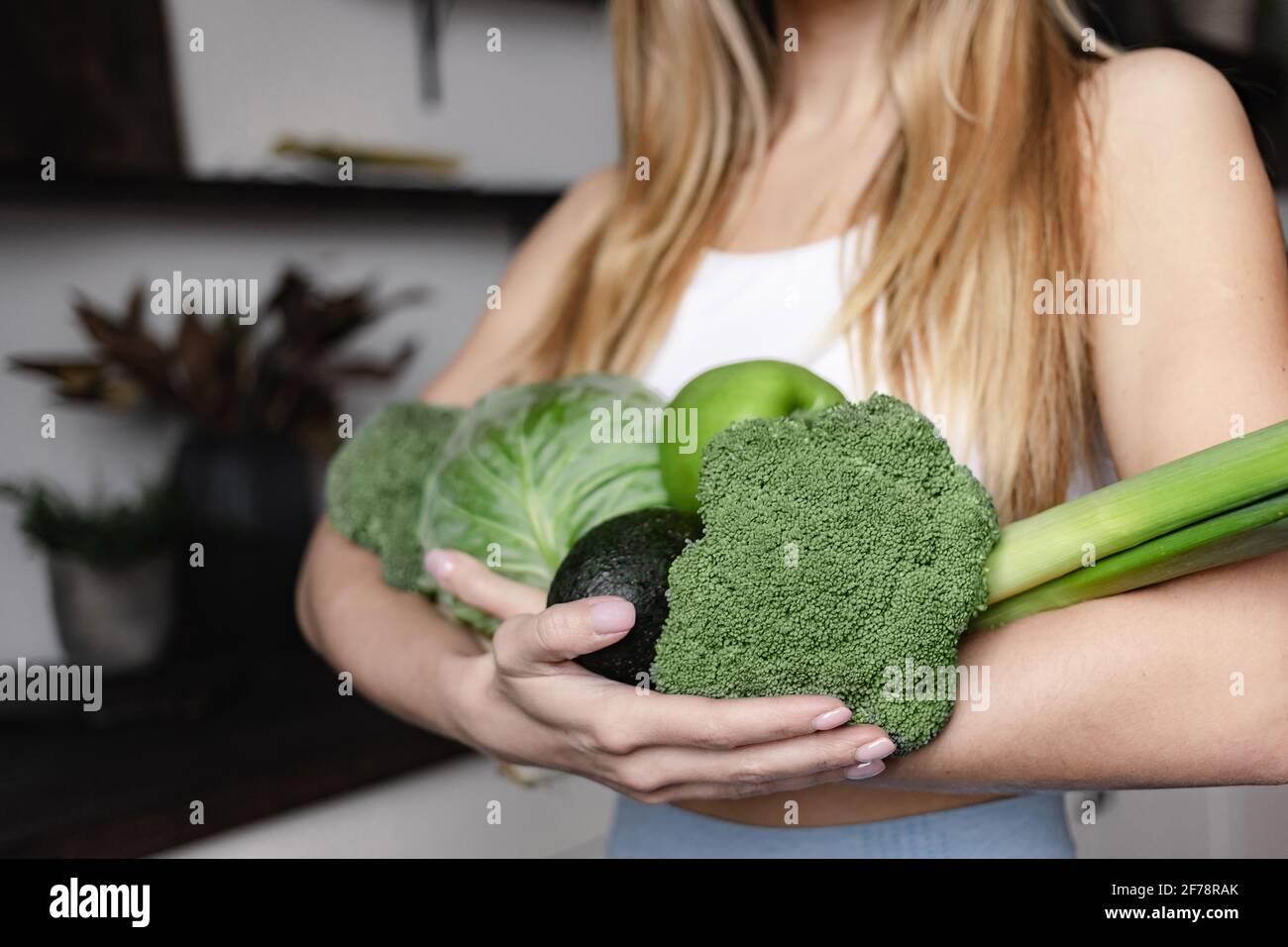 Una donna che si occupa di fitness è piena di verdure fresche verdi crude, broccoli, avocado, mela, porro, cavolo. Disintossicare sano cibo vegano dieta. Foto Stock