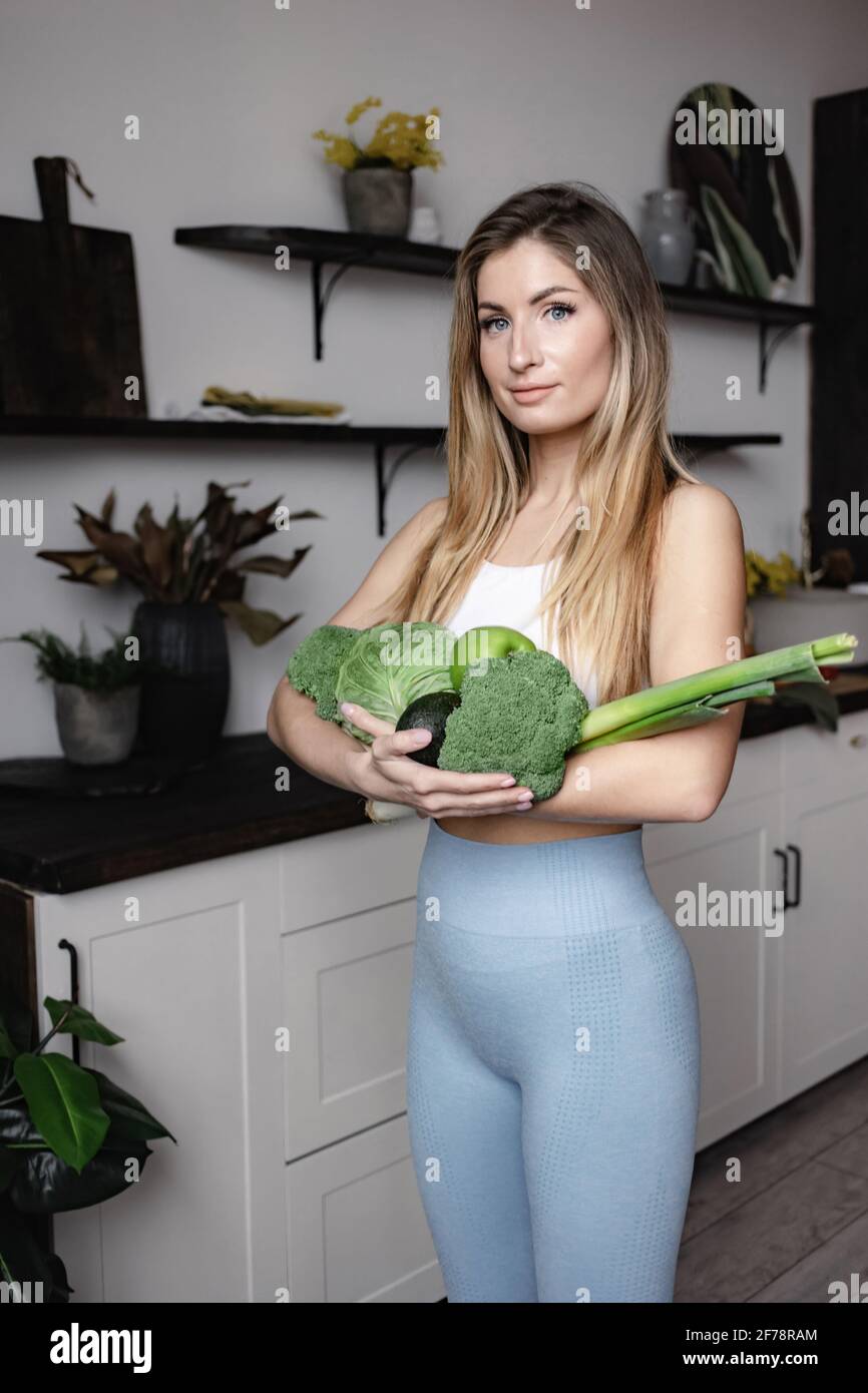 Una donna che si occupa di fitness contiene una ricca di verdure fresche verdi grezze: Broccoli, avocado, mela, porro, cavolo. Disintossicare sano cibo vegano dieta. Foto Stock