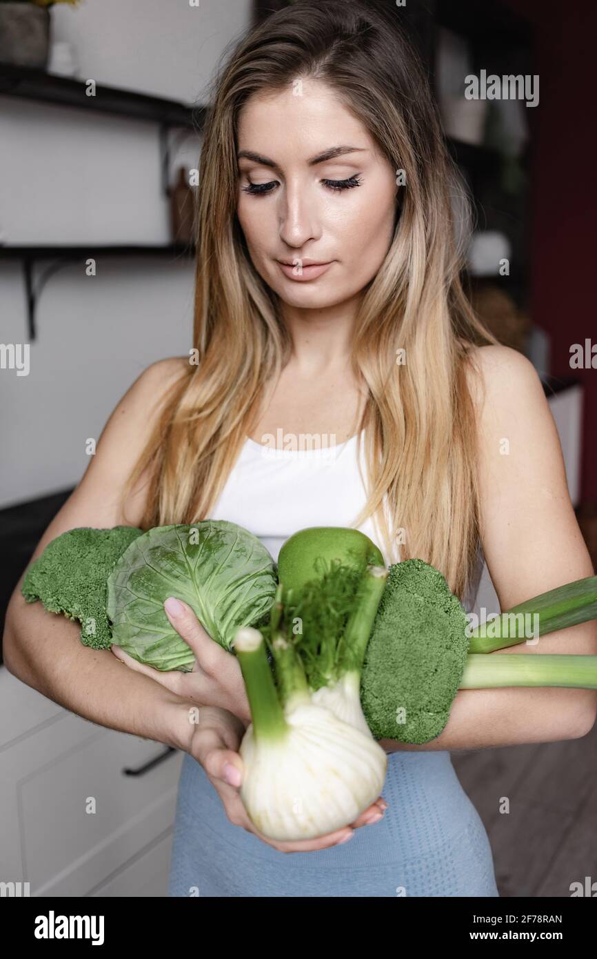 Una donna di idoneità tiene un pieno di verdure verdi grezze fresche- finocchi, broccoli, avocado, mela, porro, cavolo. Disintossicare sano cibo vegano dieta. Foto Stock