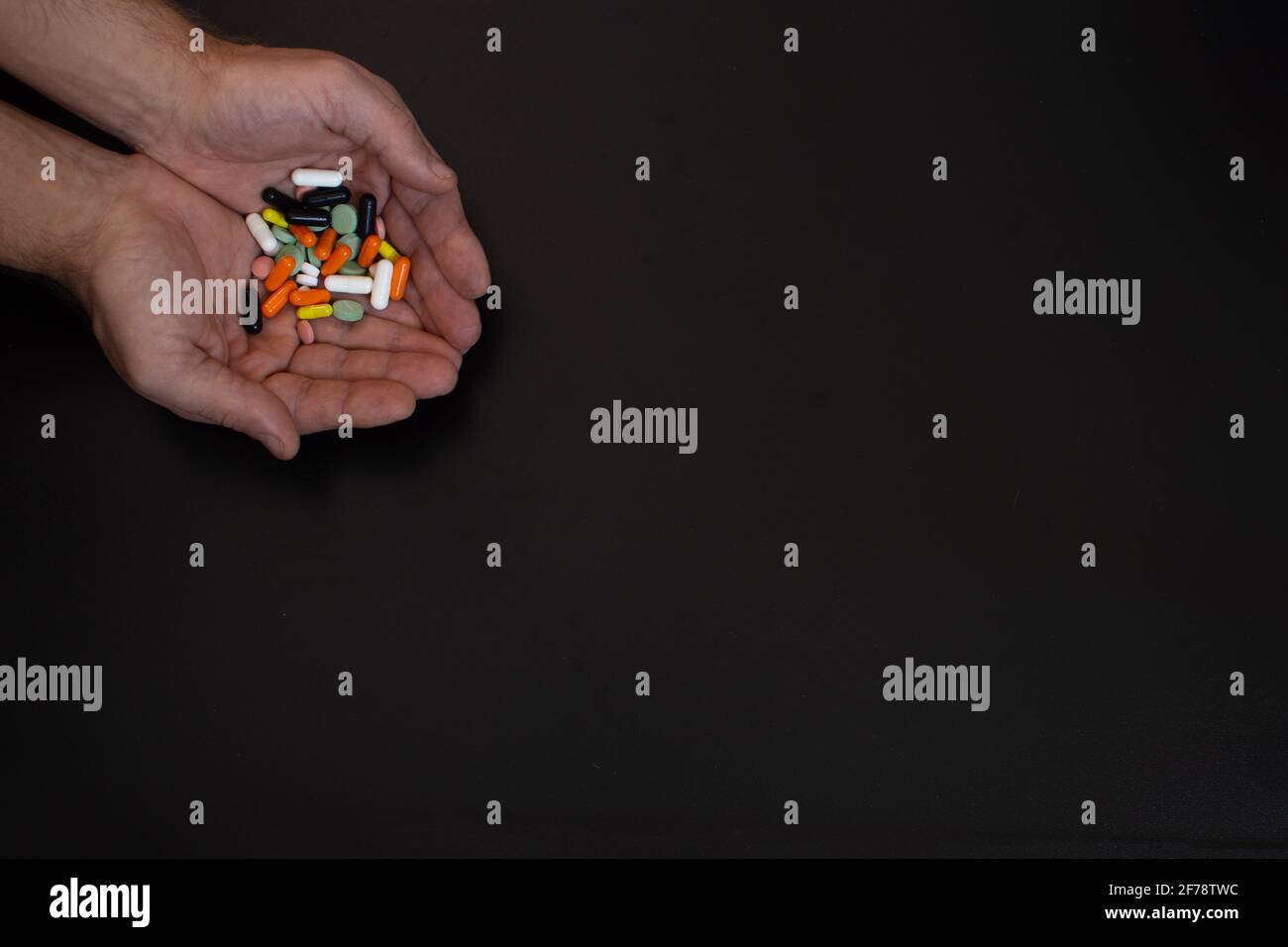 una manciata di pillole nelle mani di un uomo Foto Stock