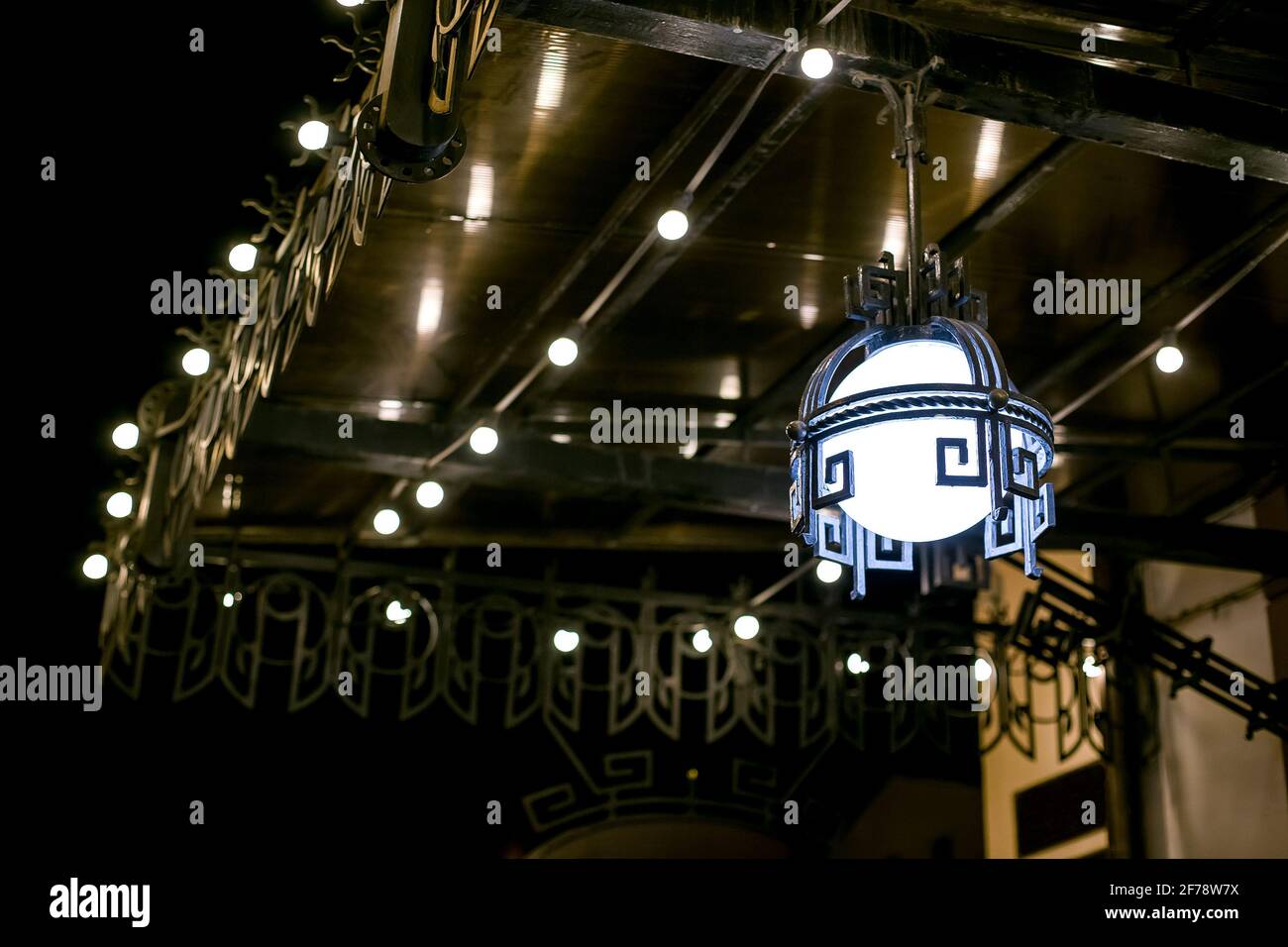 baldacchino in ferro forgiato con lanterna decorativa in stile retrò all'ingresso dell'edificio con lampade luminose di notte. Foto Stock