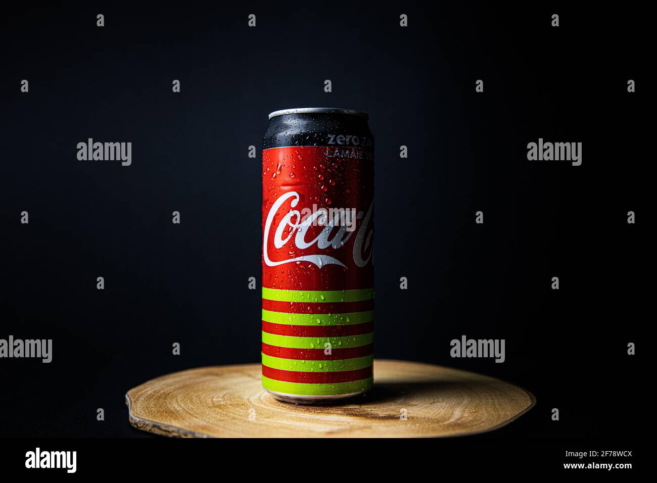 Galati, Romania, 13 aprile 2021 : lattina di Coca Cola posta su un piatto di legno in una bella luce con uno sfondo nero-bluastro Foto Stock
