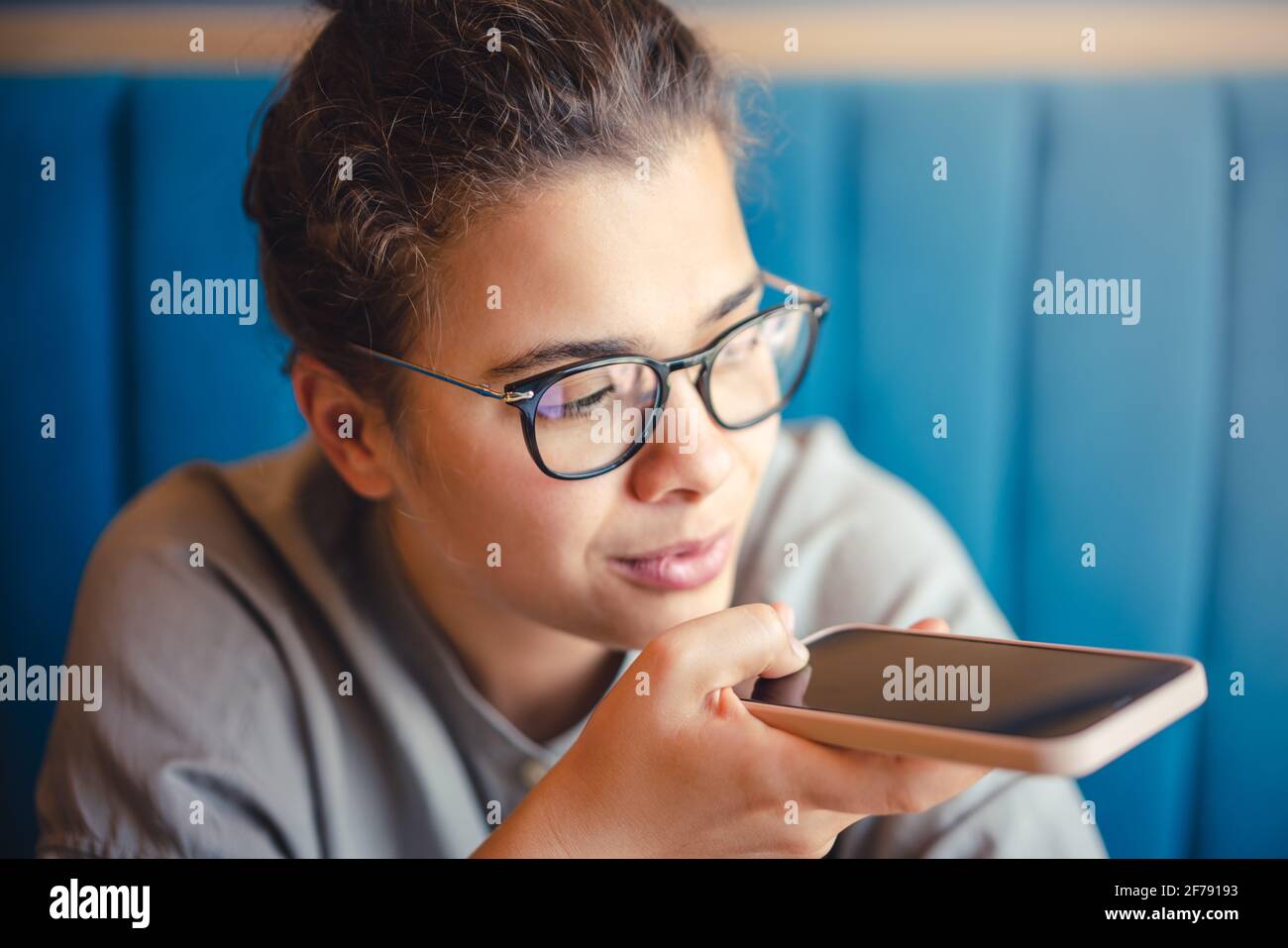 Donna in occhiali che registra un messaggio audio vocale con il cellulare telefono Foto Stock
