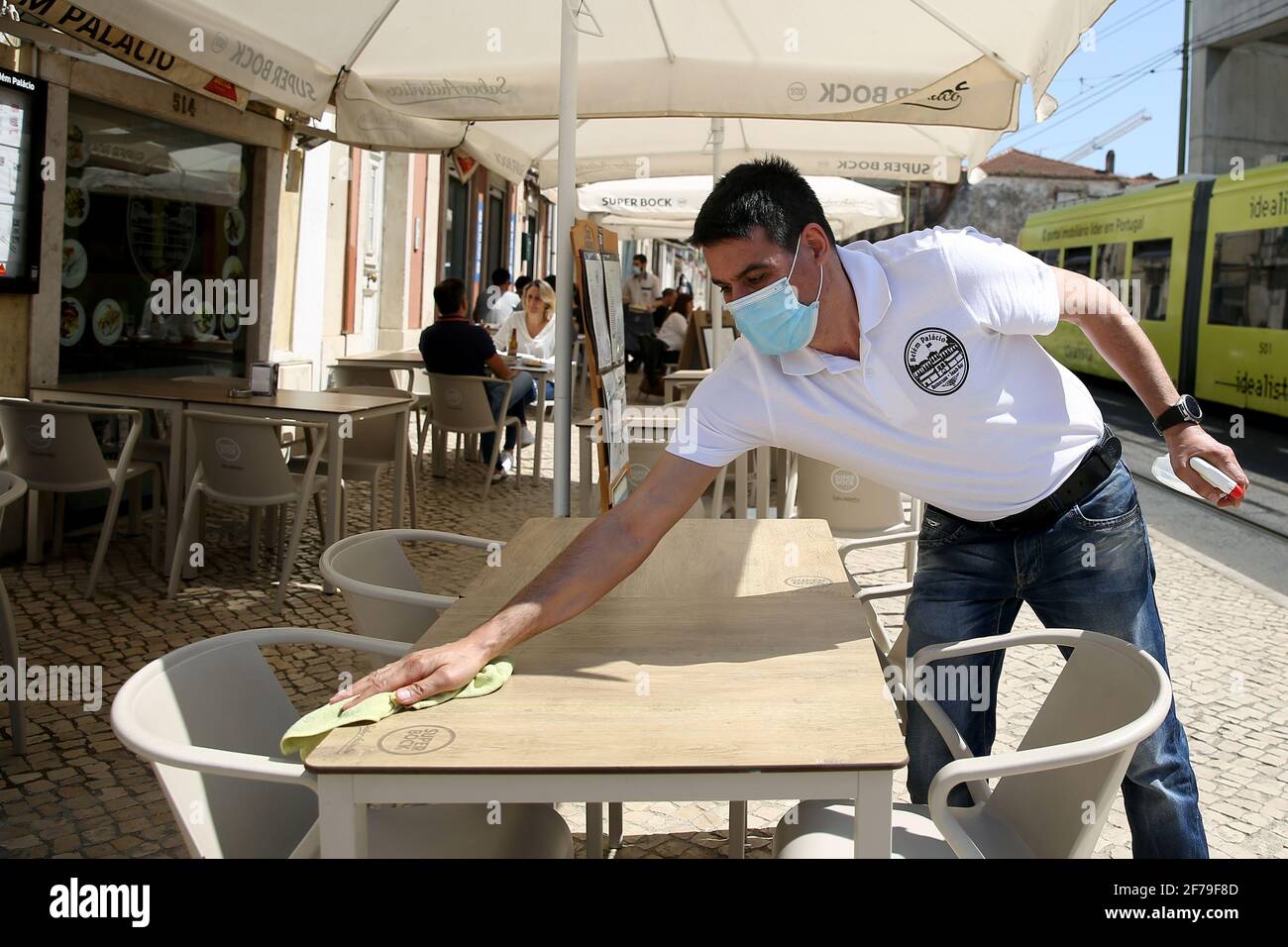 Lisbona, Portogallo. 5 Aprile 2021. Un cameriere pulisce i tavoli sulla terrazza del ristorante a Lisbona, Portogallo, 5 aprile 2021. Lunedì il presidente portoghese Marcelo Rebelo de Sousa ha chiesto "uno sforzo nazionale da parte di tutti per evitare battute d'arresto" all'inizio della seconda fase del programma di deconfinamento del paese. Credit: Pedro Feuza/Xinhua/Alamy Live News Foto Stock