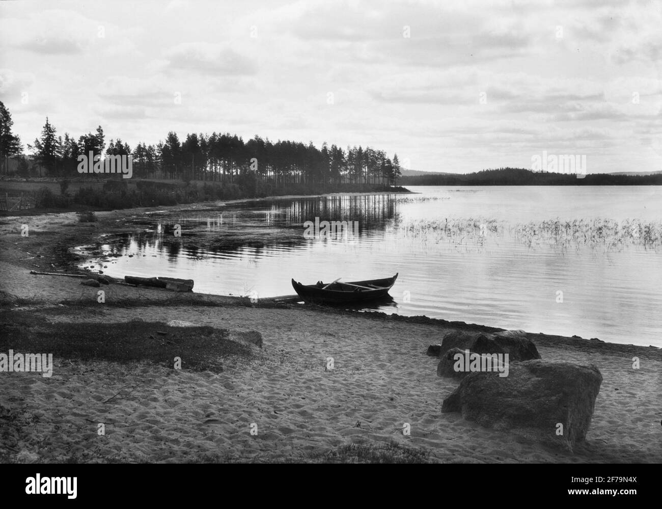 Diapostiv, immagine della finestra con motivi naturali. Canoa da caccia (Eka, barca a remi) sulla spiaggia sabbiosa accanto al lago. Foto Stock