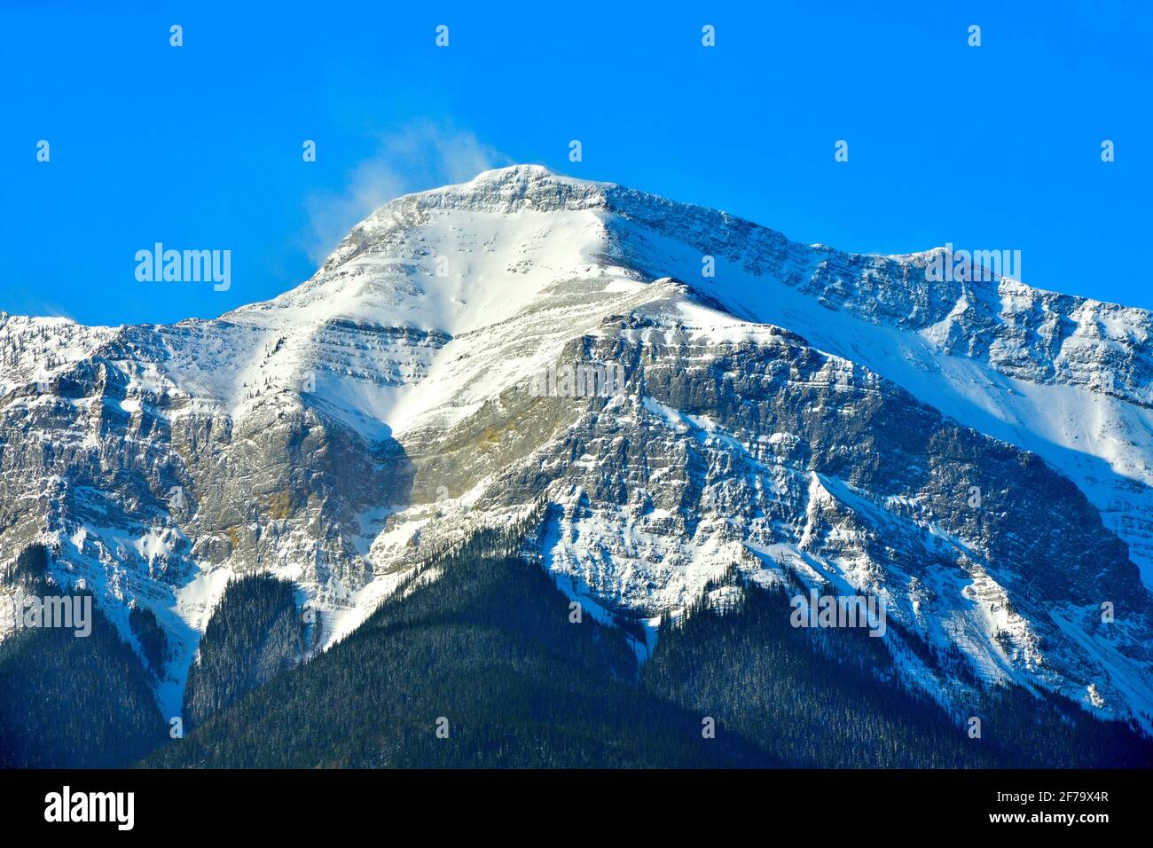 Un'immagine di una vetta rocciosa innevata con un Cielo blu luminoso sullo sfondo nella campagna Alberta Canada Foto Stock