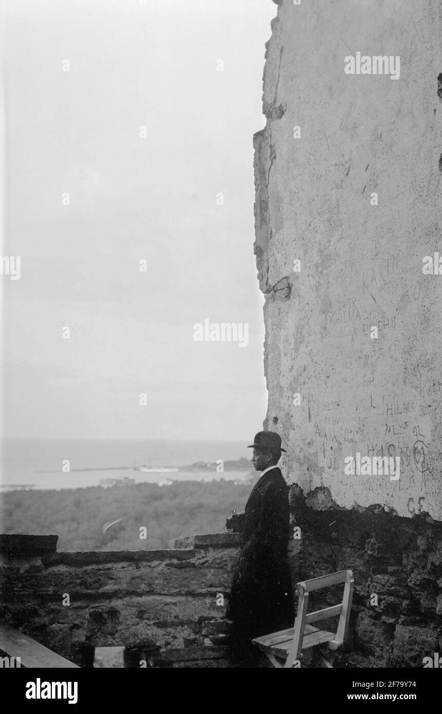 Le immagini della regina Vittoria. Un uomo con macchina fotografica in mano in piedi su un'alta montagna che guarda sul mare, dalle rovine del castello di Borgholms 69. Foto Stock