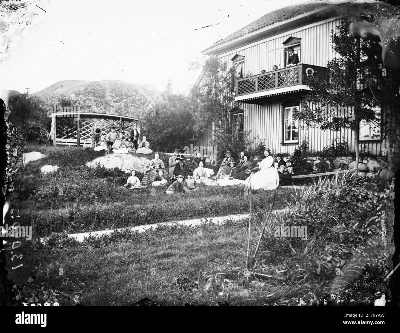 Al bagno di mare a Lysekil siede un gruppo di persone sull'erba e ascolta un uomo che legge in alto da un libro? La casa sullo sfondo è costruita da Johan Gabriel Mollen. Foto Stock