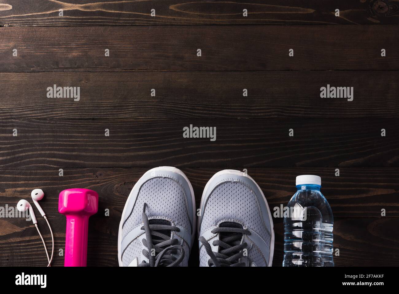 Abbina scarpe sportive, cuffie, manubri e bottiglia d'acqua su sfondo tavolo in legno nero, sneakers Grey e accessori in PALESTRA, Healt Foto Stock