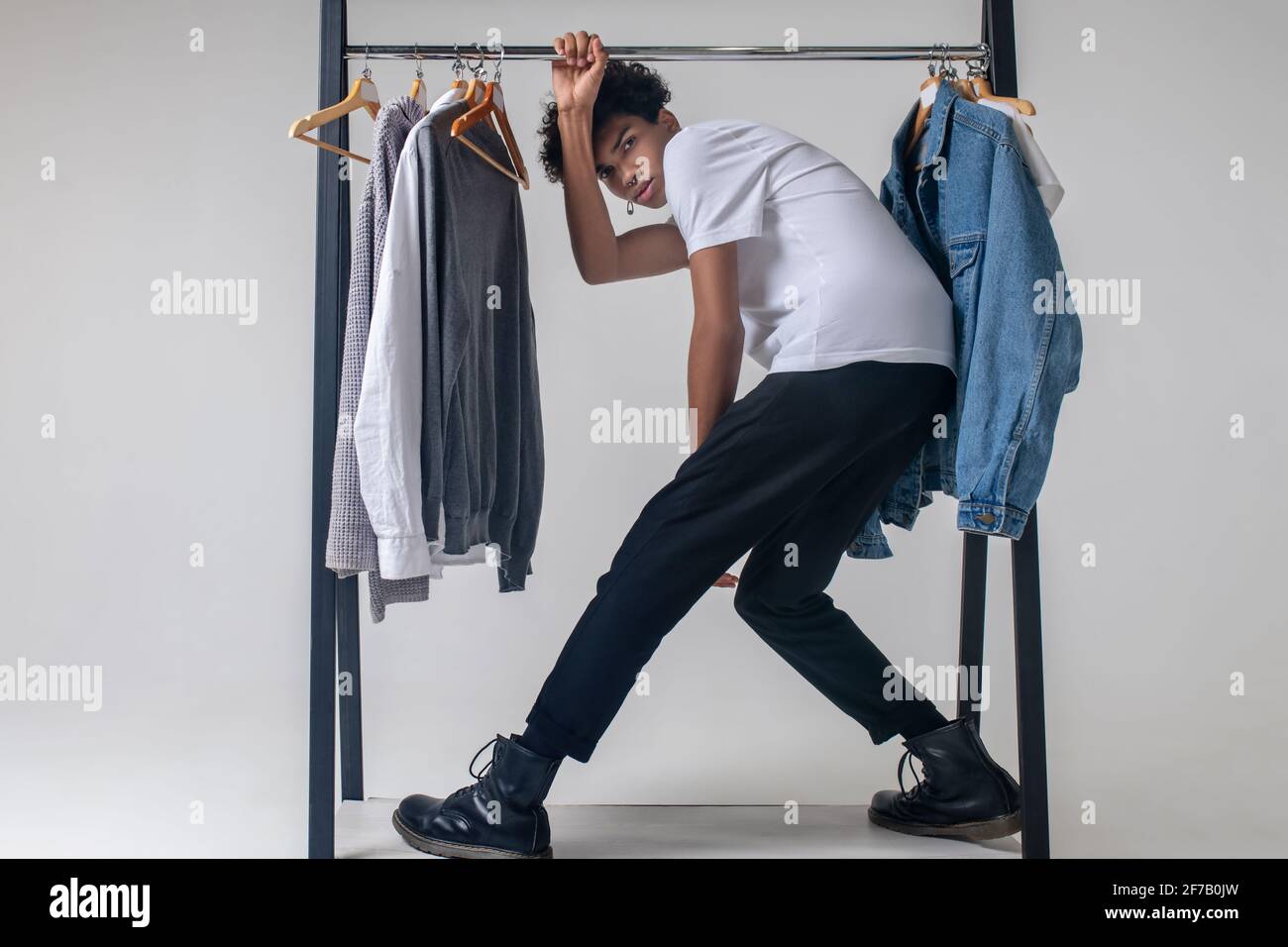 Giovane ragazzo afroamericano che tiene appendiabiti e si appoggia avanti Foto Stock