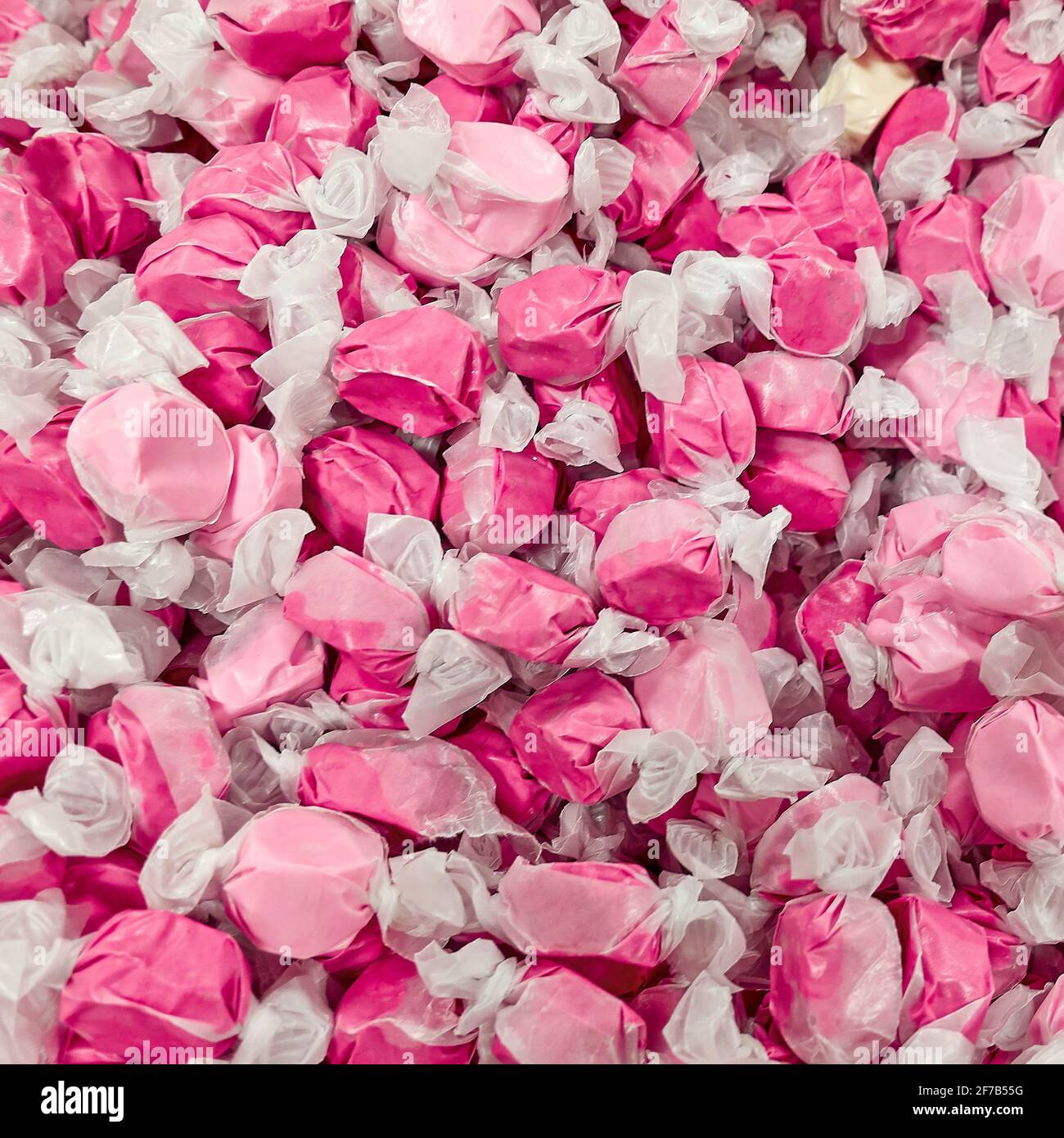 Taffy di acqua salata rosa in involucri bianchi caramelle gommose e appiccicose Foto Stock