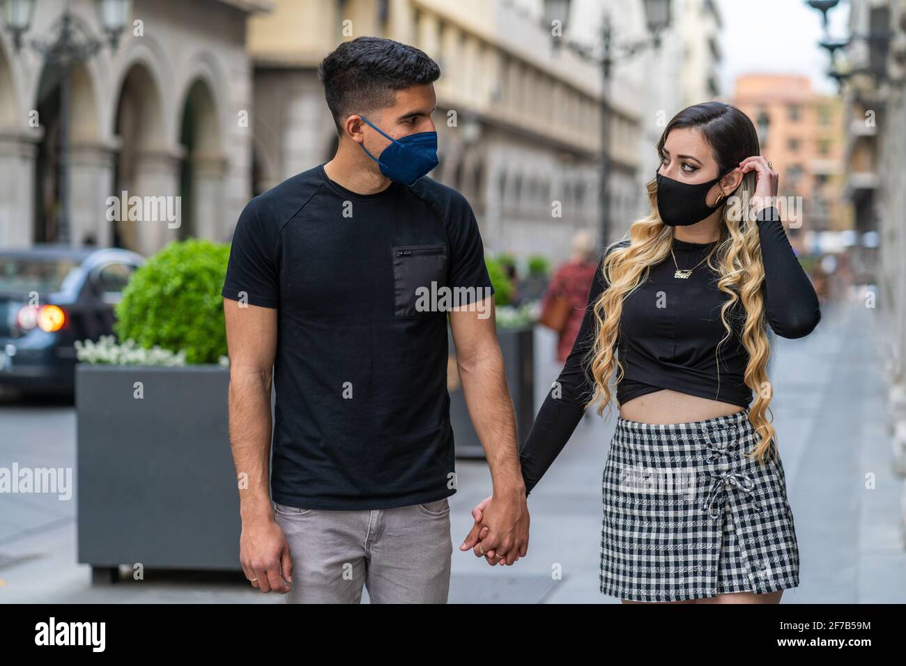Coppia innamorata di una maschera a causa della pandemia di Sars-COV2. Camminando lungo la strada Foto Stock