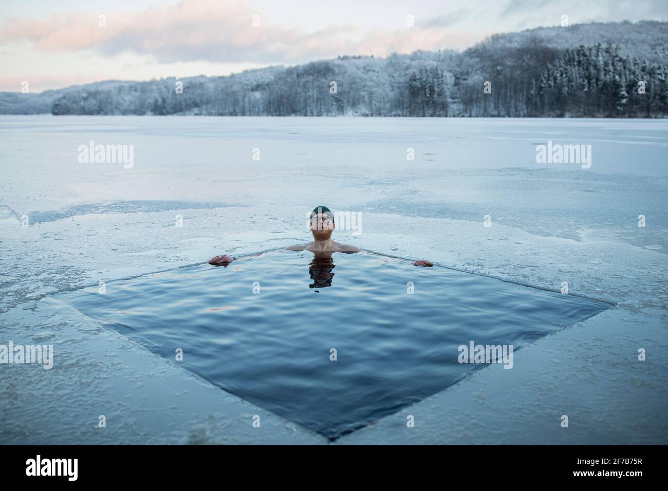 Uomo che nuota in lago ghiacciato Foto Stock