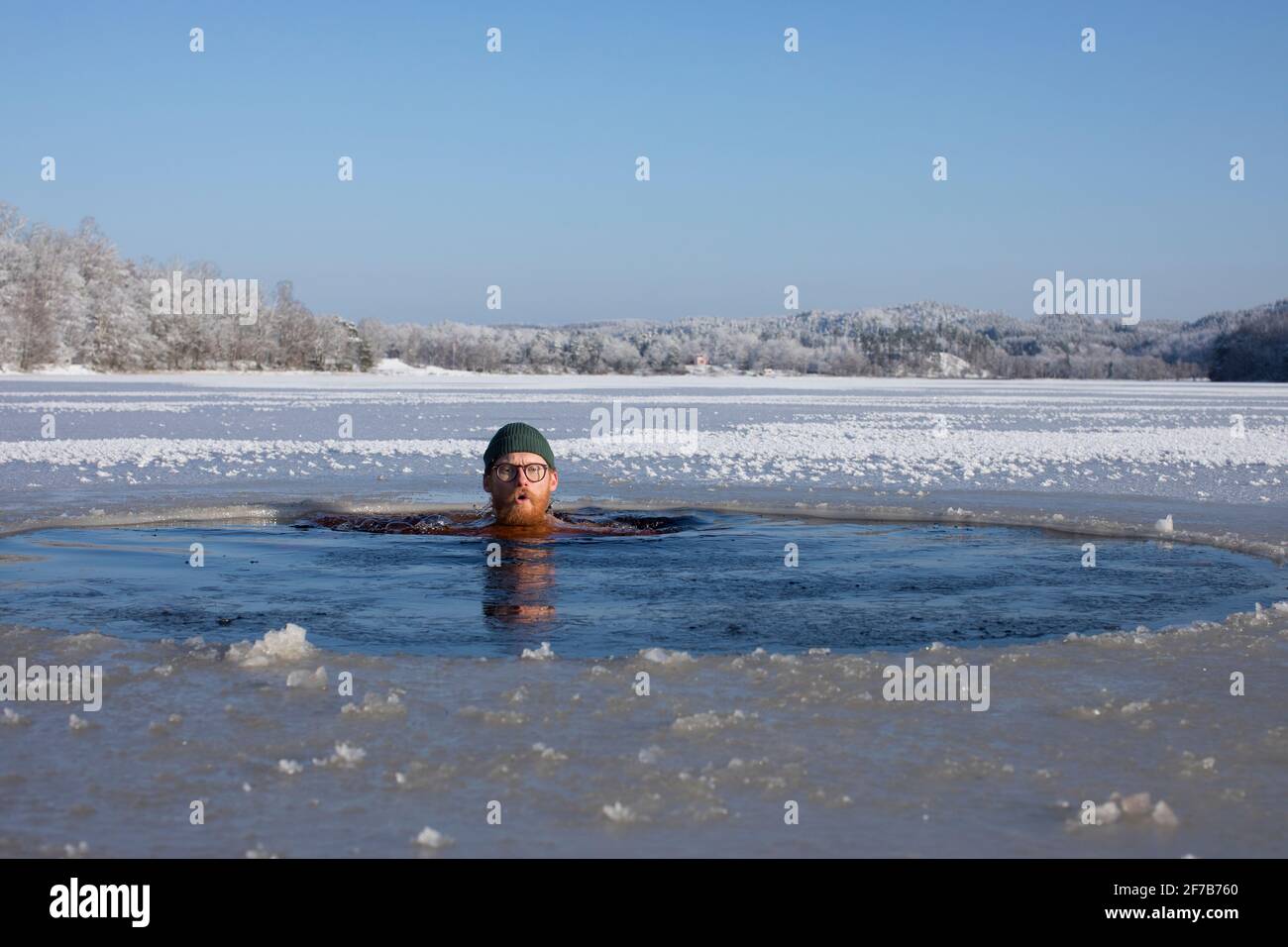 Uomo che nuota in lago ghiacciato Foto Stock