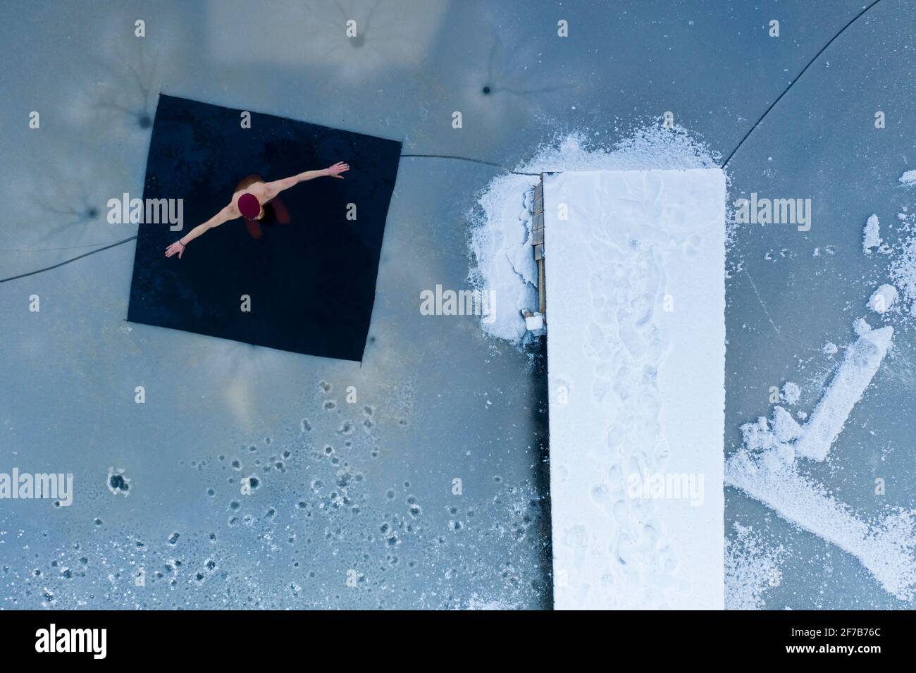 Uomo che nuota in lago ghiacciato Foto Stock