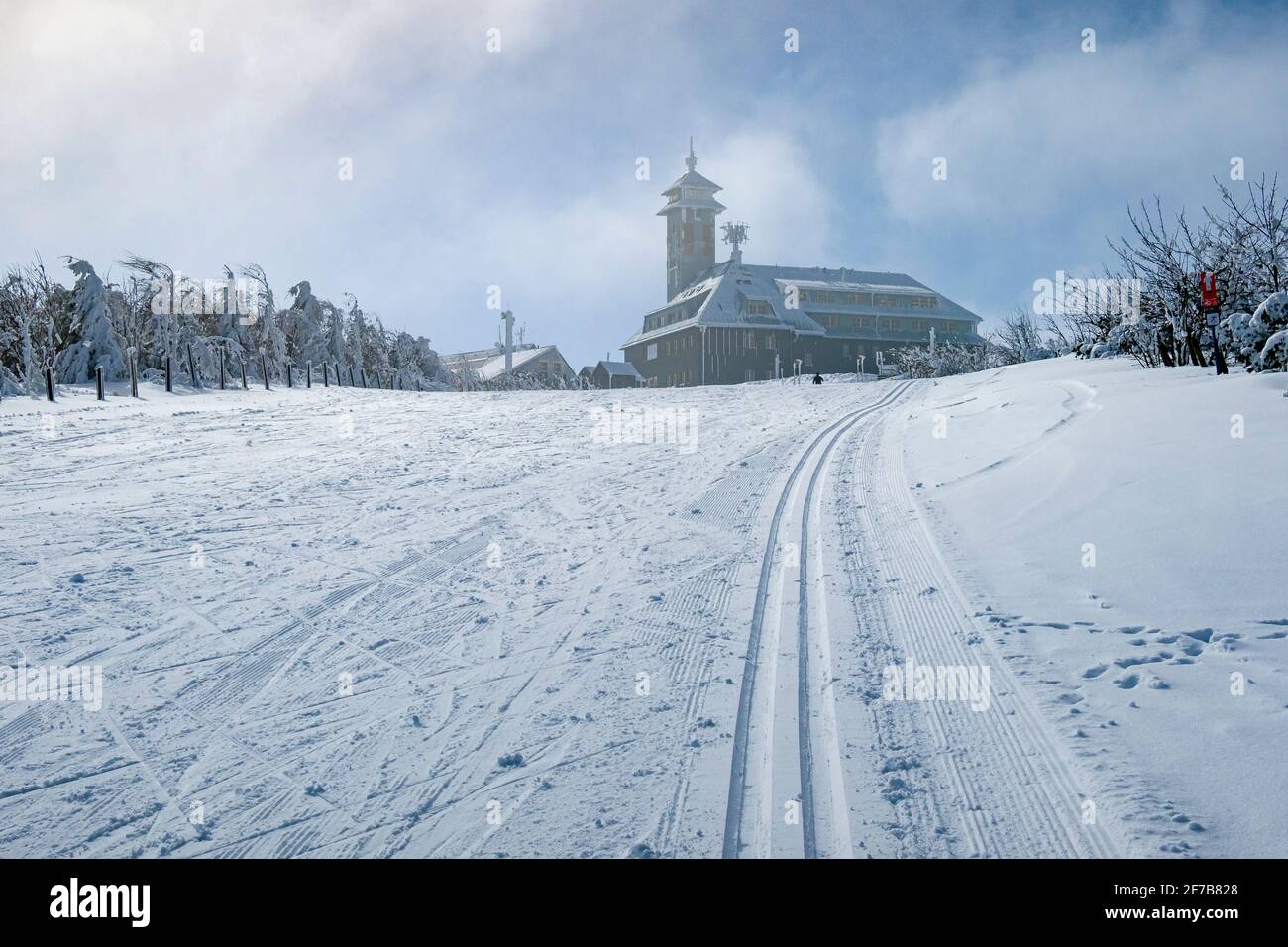 Pista da sci di fondo innevata che conduce fino alla cima del monte Fichtelberg, l'edificio Fichtelberghaus in lontananza, in inverno. Foto Stock
