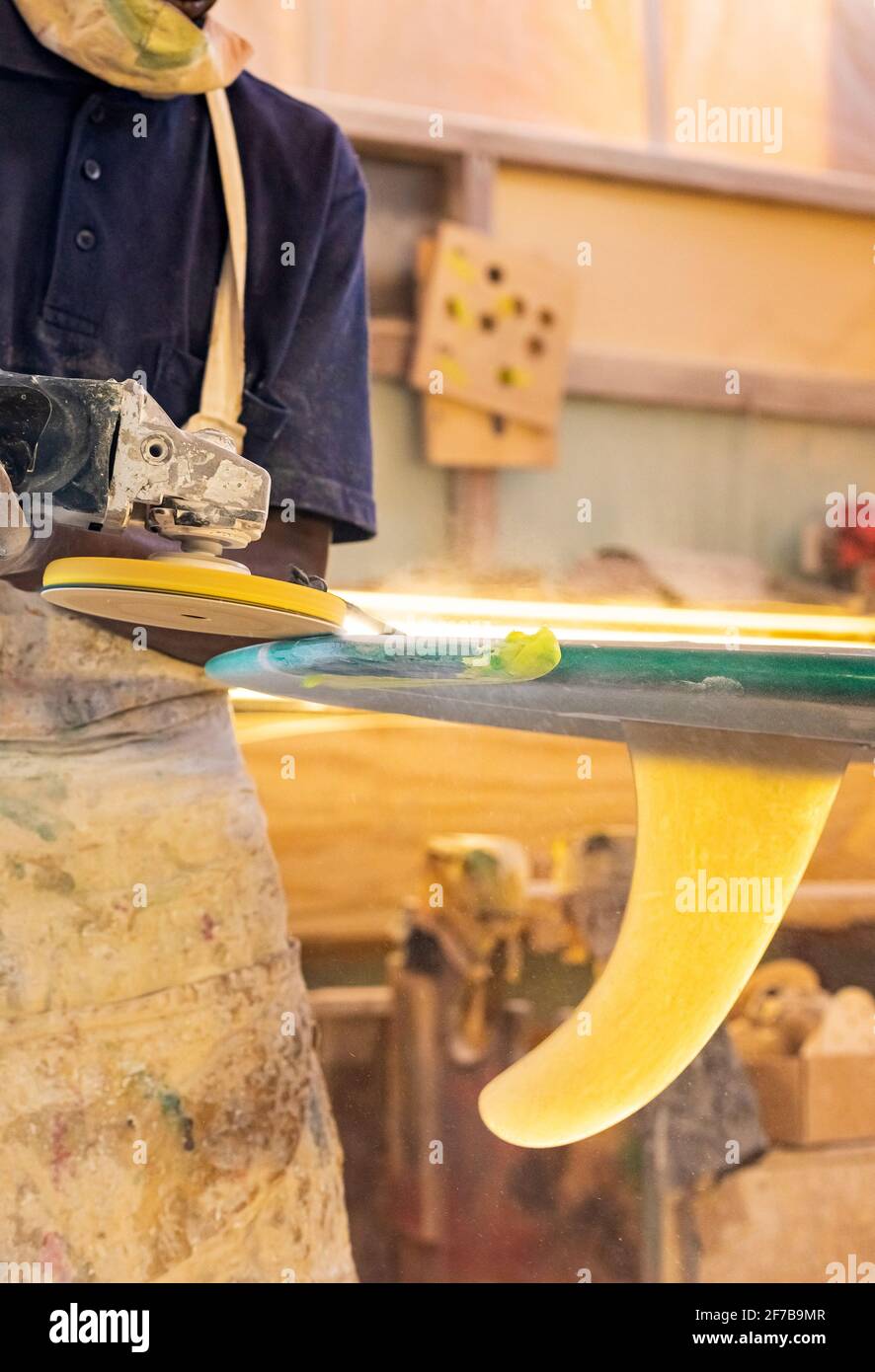 Primo piano di un artigiano africano tavola da surf Shaper lavorare in un'officina di riparazione Foto Stock