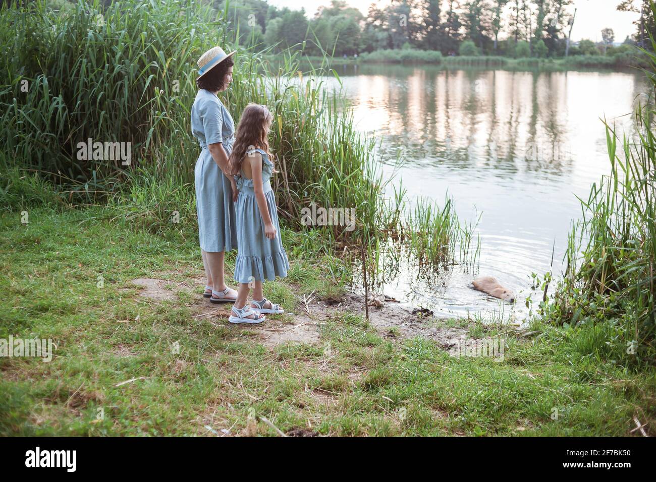 Una ragazza si trova sulla riva del lago e. guarda la nutria nell'acqua Foto Stock