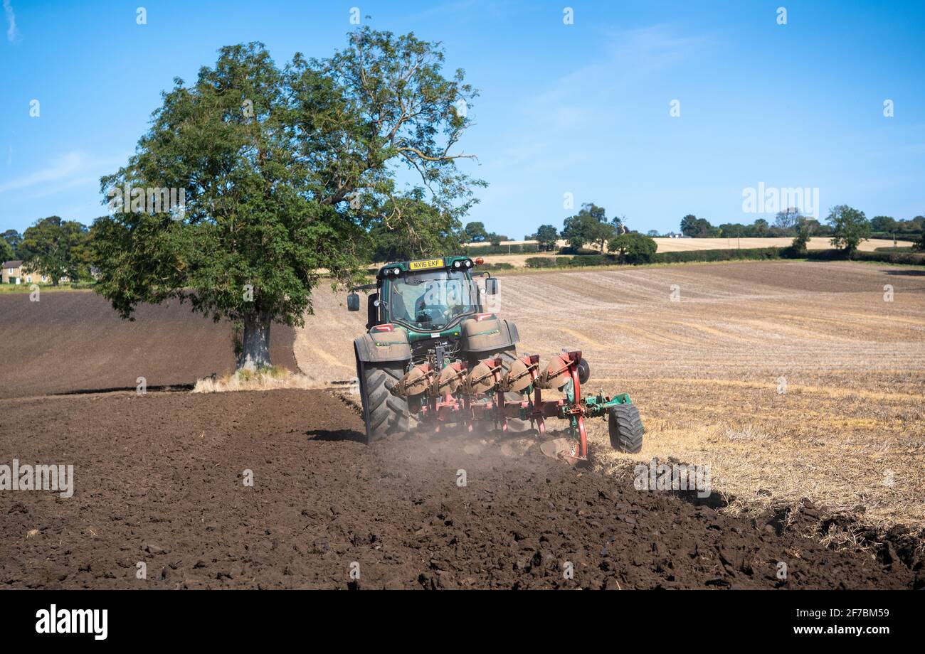 Aratura dell'agricoltore nelle stoppie dopo la raccolta del prodotto, utilizzando un trattore Valtra e un aratro a 5 solchi. North Yorkshire, Regno Unito. Foto Stock