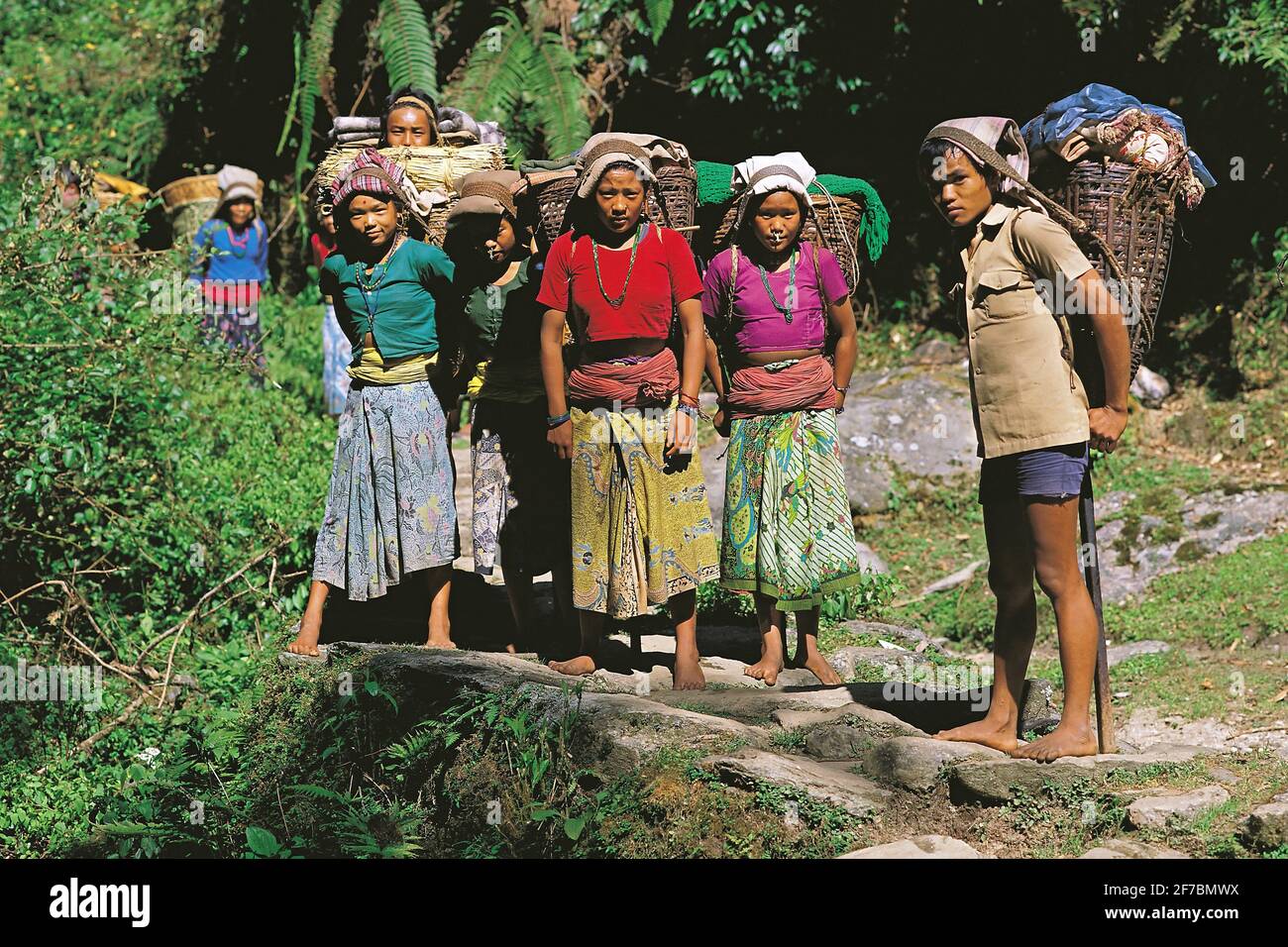 Gruppo di giovani in un viaggio di commercio che trasportano le merci di ritorno al loro villaggio domestico nella regione di Makalu del Nepal orientale, Nepal, Parco Nazionale di Makalu Barun Foto Stock