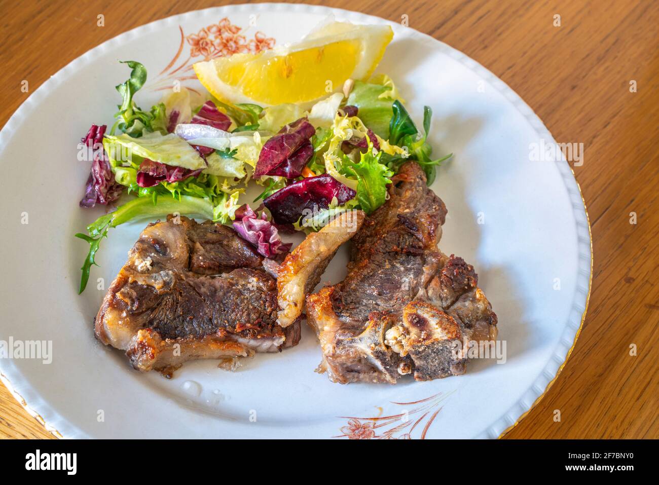 Tipico piatto pasquale in Abruzzo, carne di agnello alla griglia e insalata mista. Abruzzo, Italia, Europa Foto Stock