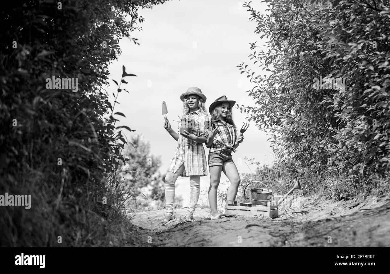 Giardinaggio di bellezza. Ecologia e protezione ambientale. I bambini tengono gli attrezzi di giardinaggio. Giorno di terra. Fattoria di famiglia di estate. Contadino delle ragazze piccole nel villaggio Foto Stock