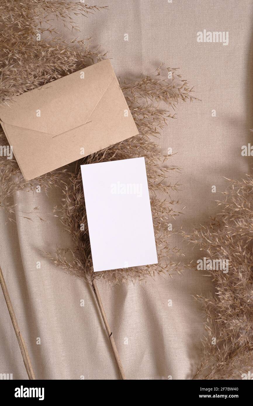 Cartoncino bianco e busta mockup con pampas asciutti erba su un tessuto di colore neutro beige Foto Stock