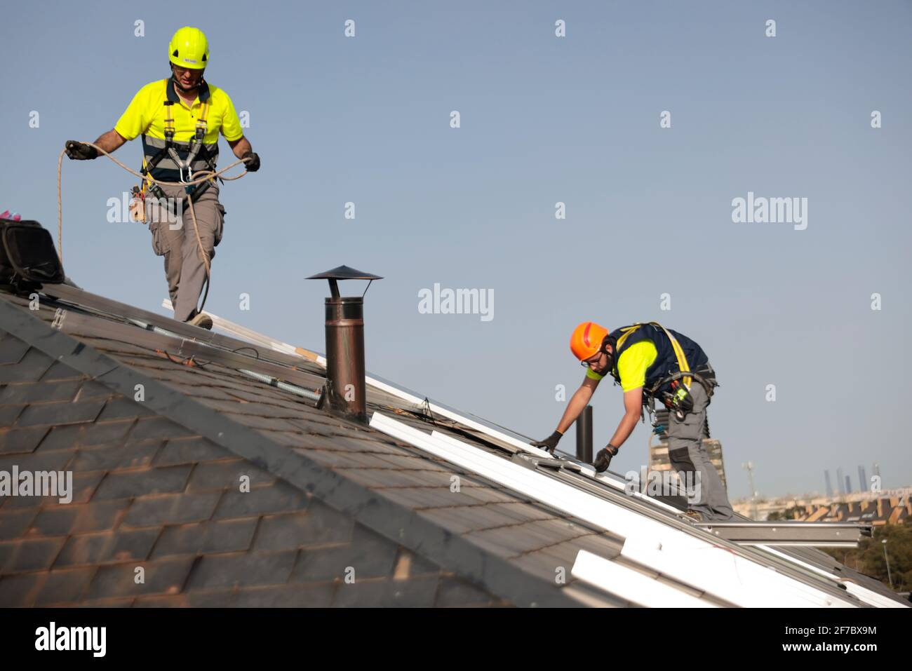 I lavoratori che indossano maschere per il viso installano pannelli solari su un tetto in una casa residenziale a Majadahonda, Madrid, Spagna. Foto Stock