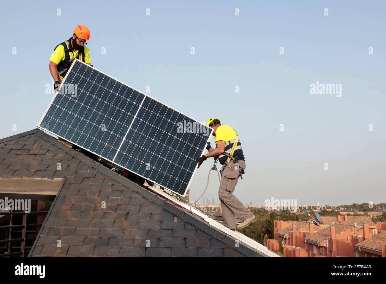 I lavoratori che indossano maschere per il viso installano pannelli solari su un tetto in una casa residenziale a Majadahonda, Madrid, Spagna. Foto Stock