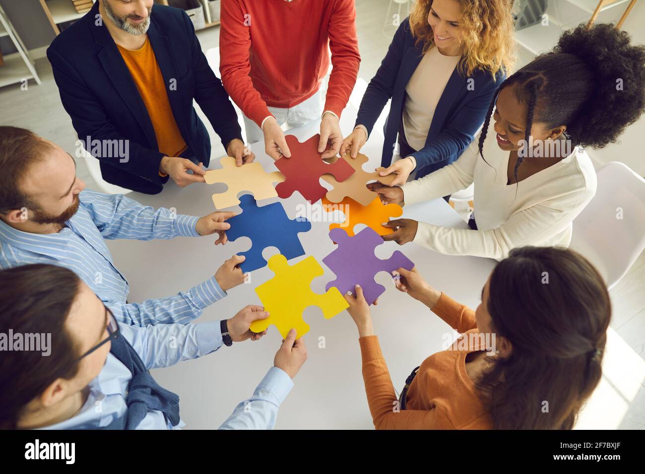 Team aziendale che collega le parti del puzzle come metafora per il lavoro di squadra, la cooperazione e la ricerca di soluzioni Foto Stock