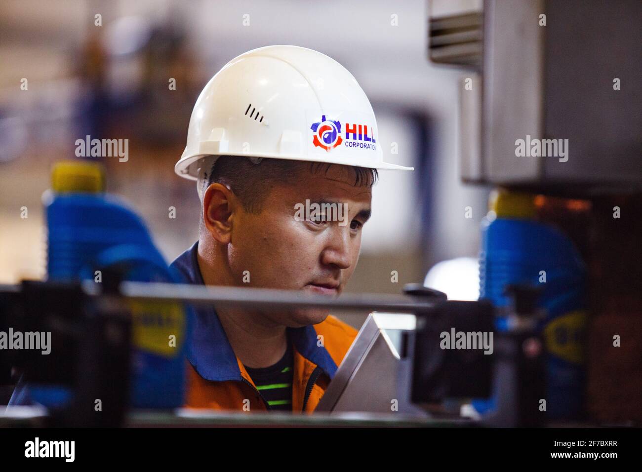 Olio motore moderno impianto di produzione. Operaio in hardhat bianco sulla linea di produzione. Controllo di qualità. Foto Stock