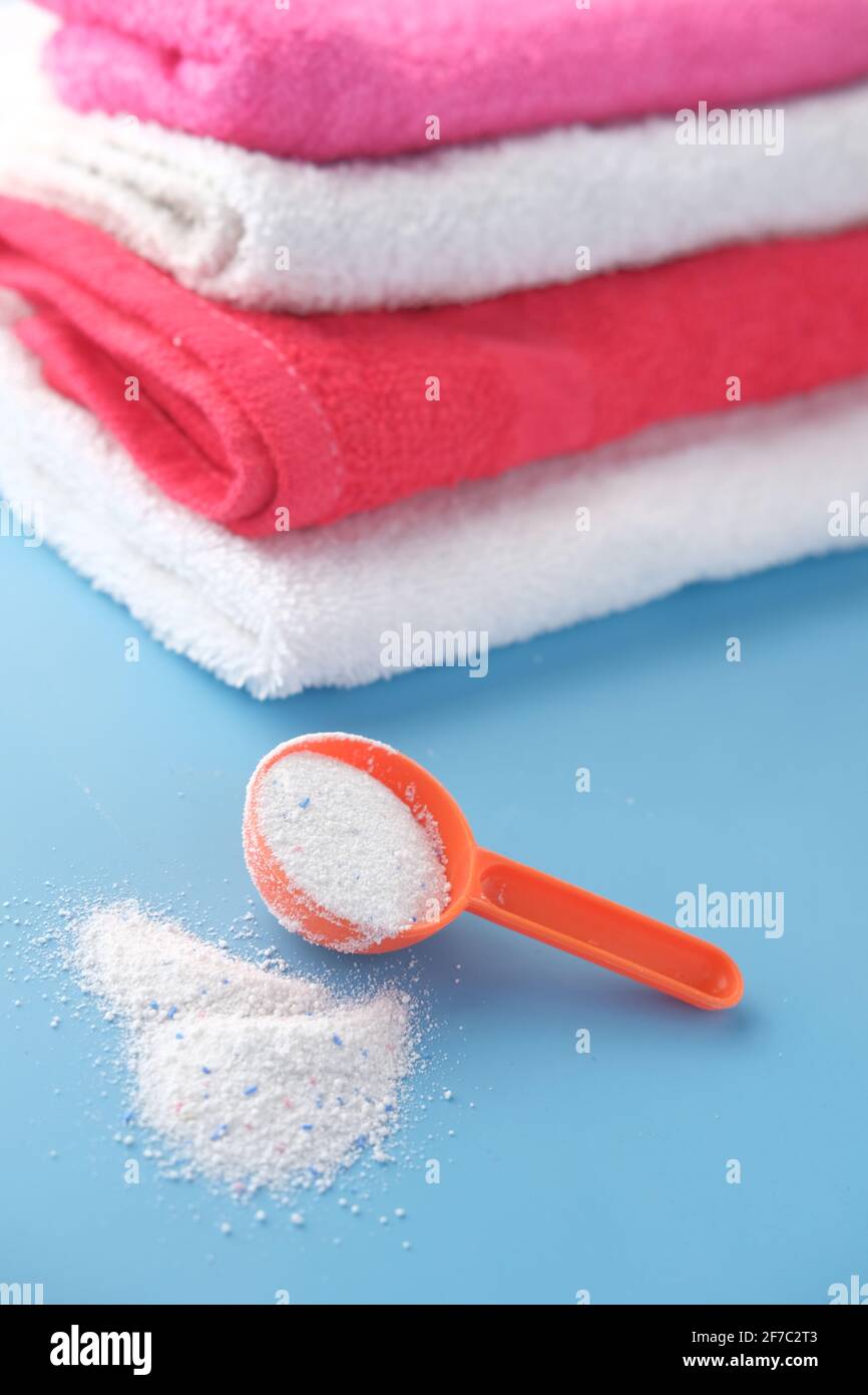 Polvere di lavaggio in cucchiaio di plastica su fondo blu Foto Stock