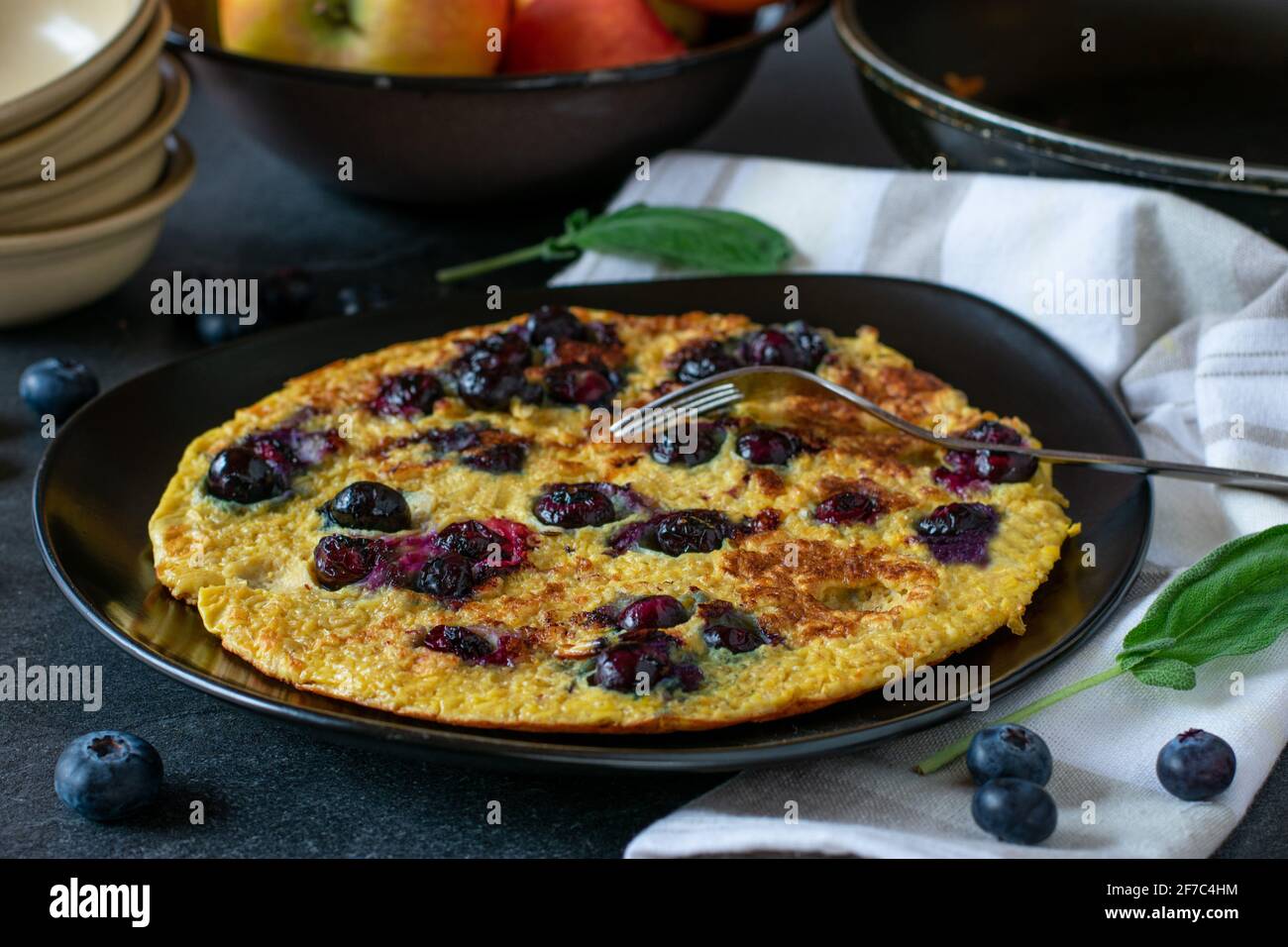 Piatto sano di pancake con un pancake di farinata d'avena condito con mirtilli e servito su un piatto su sfondo tavolo da cucina Foto Stock