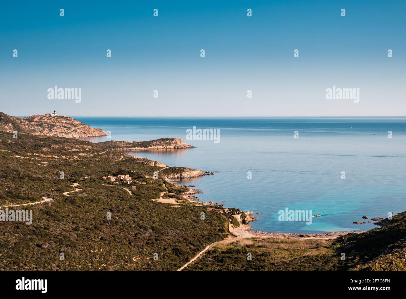 Una canoa Outrigger si trova in una baia turchese traslucida fuori La costa di la Revellata vicino Calvi nella Balagne Regione della Corsica sotto una chiara sk blu Foto Stock