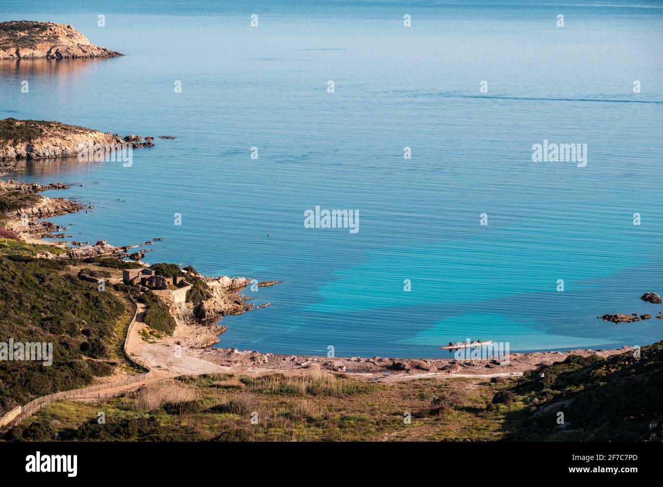 Una canoa Outrigger si trova in una baia turchese traslucida fuori La costa di la Revellata vicino Calvi nella Balagne Regione della Corsica sotto una chiara sk blu Foto Stock