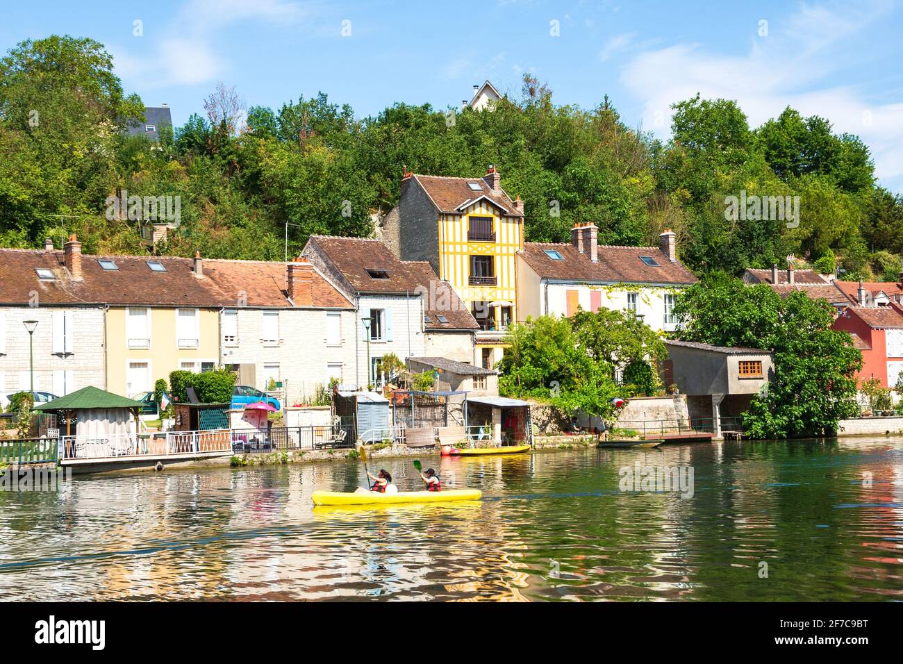 NEMOURS, FRANCIA - 7 LUGLIO 2019: Le persone che pagaiano canoa sul fiume Loing e case pittoresche lungo l'acqua. Nemours è una città medievale Foto Stock