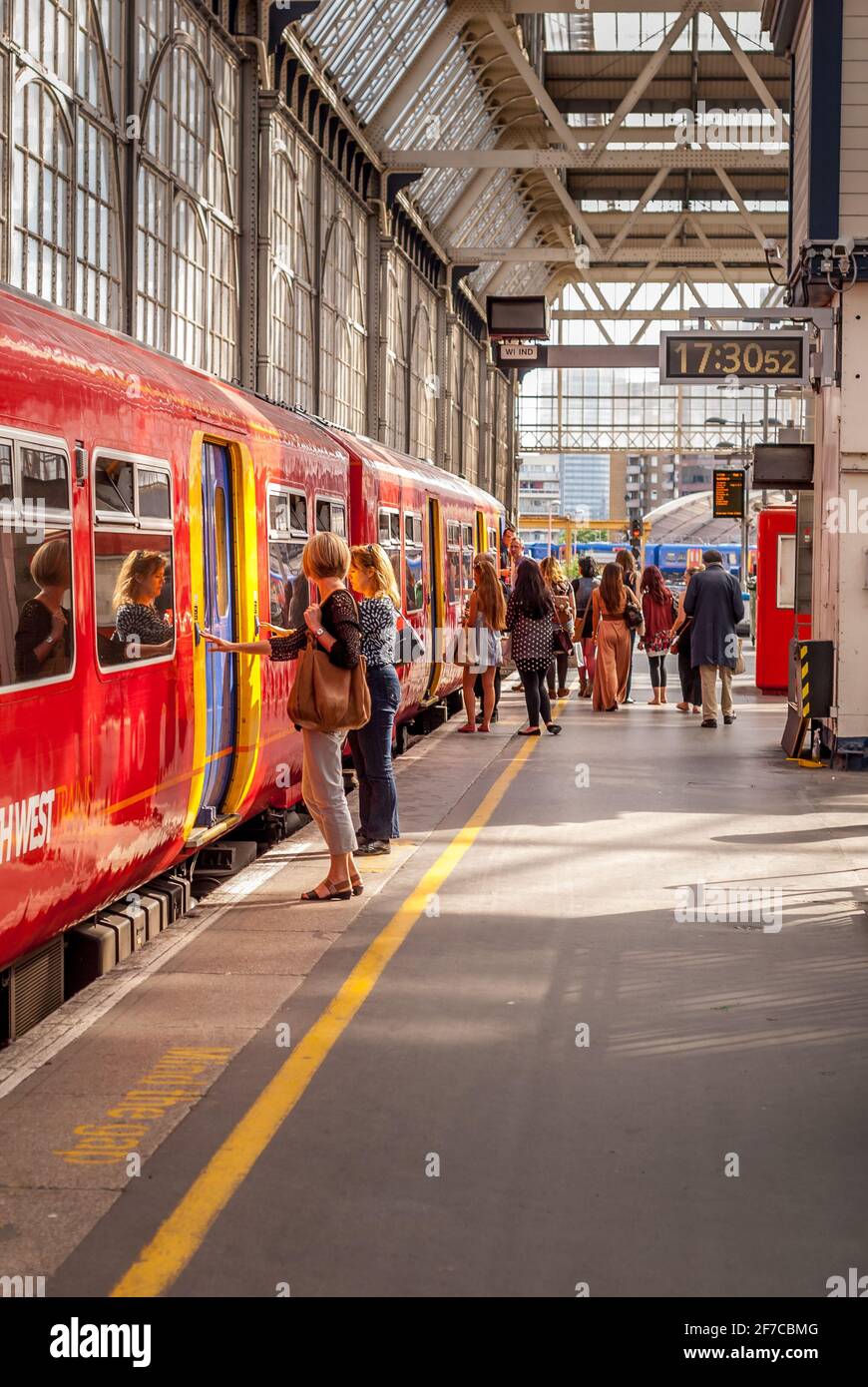 I passeggeri salgono a bordo del treno della South Western Railway al binario occupato della stazione di Londra Foto Stock