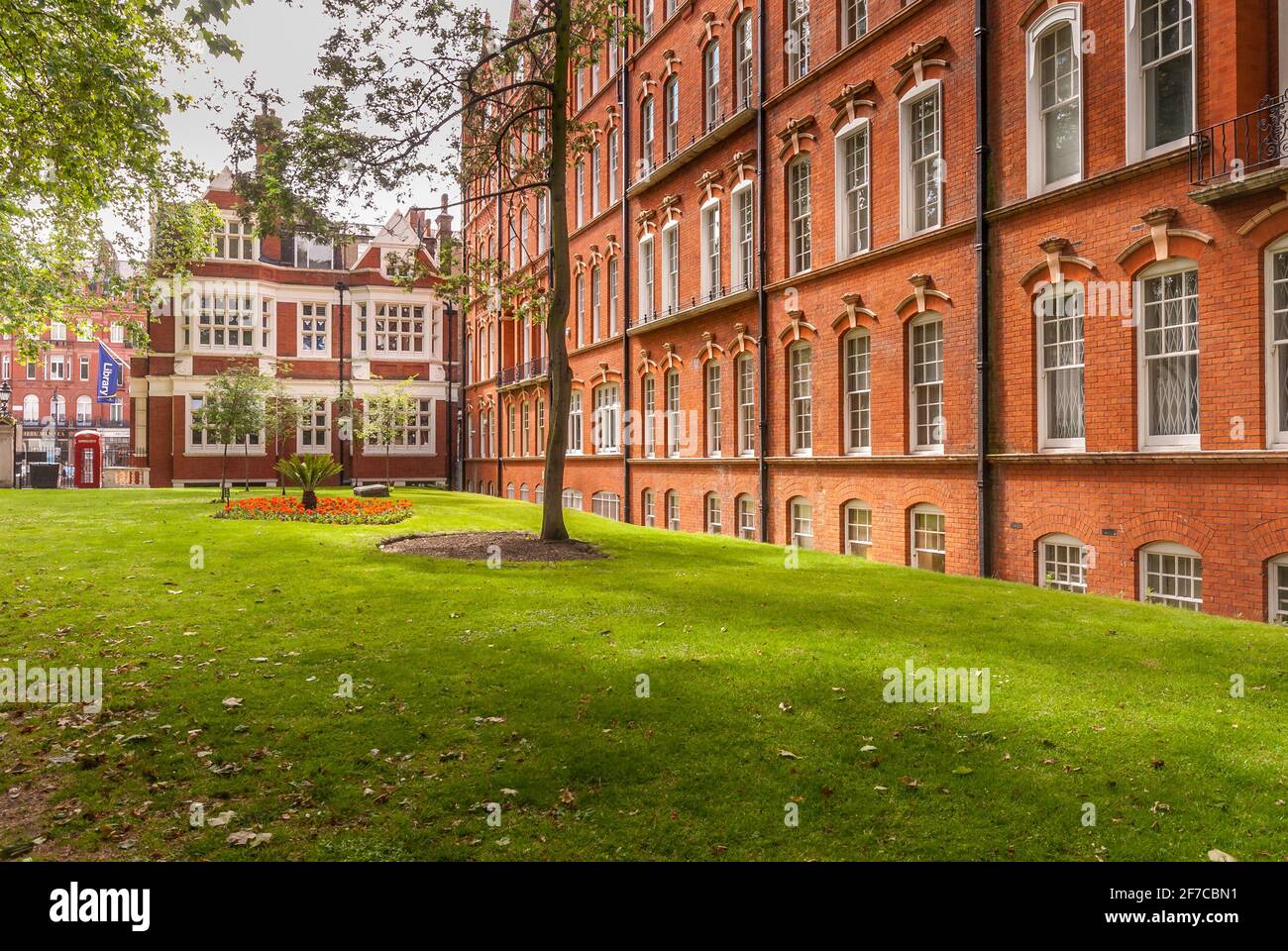 Edifici storici in mattoni rossi con prato ben curato e alberi nel cortile centrale di Londra Foto Stock