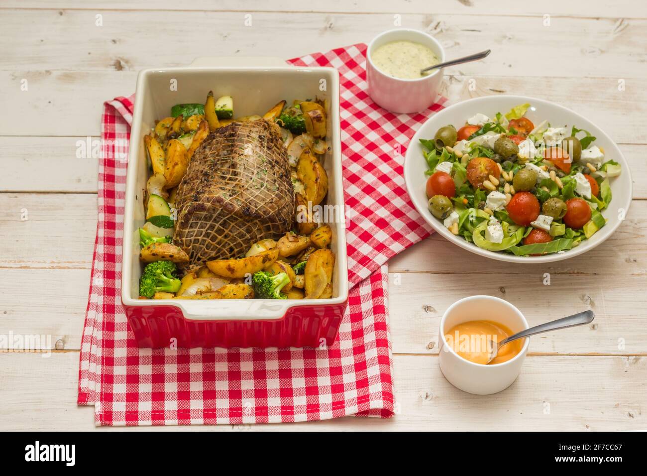 Involtini di maiale arrostiti al forno, serviti con patate, verdure, salse e insalata fresca Foto Stock
