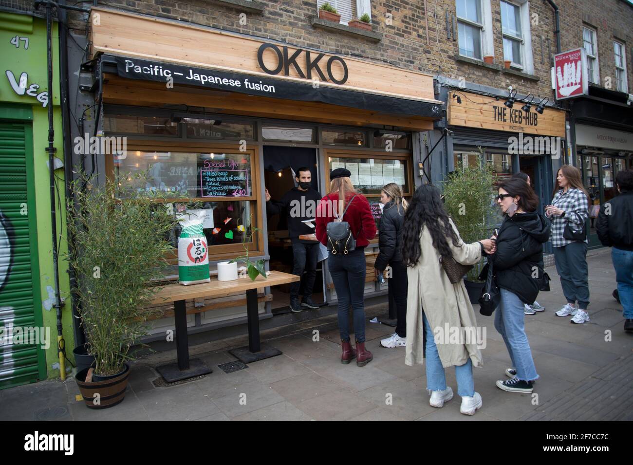Londra, Inghilterra, Regno Unito. Hackney. Campi di Londra. Mercato di Broadway. Giovani in strada in attesa di take-away di fronte Okko, giapponese e Pacifico Foto Stock