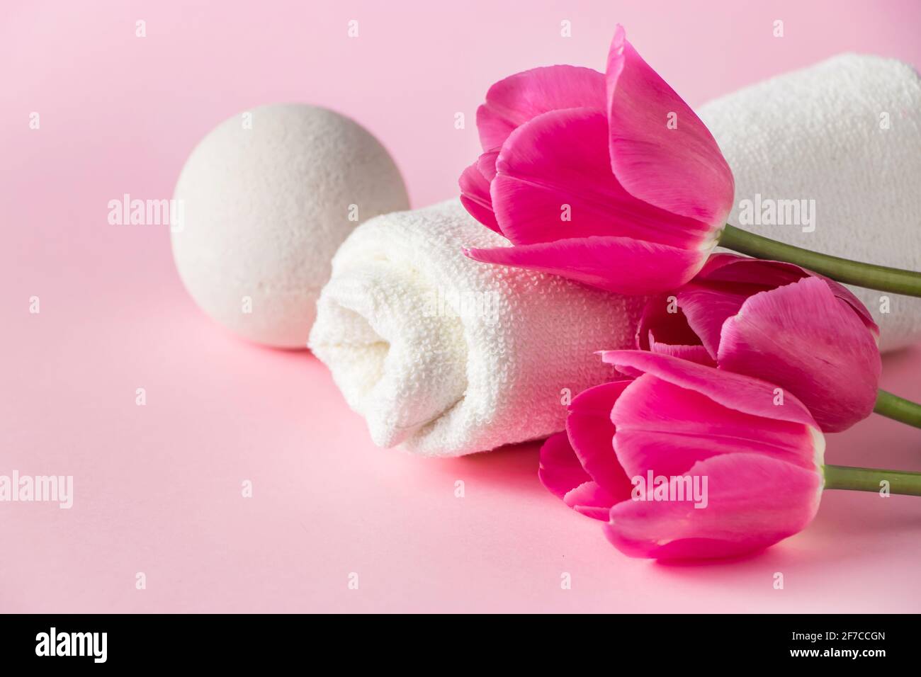 Prodotti per la cura della pelle Spa su sfondo rosa. Cosmetici naturali e tulipani rossi. Posiziona per il testo. Foto Stock