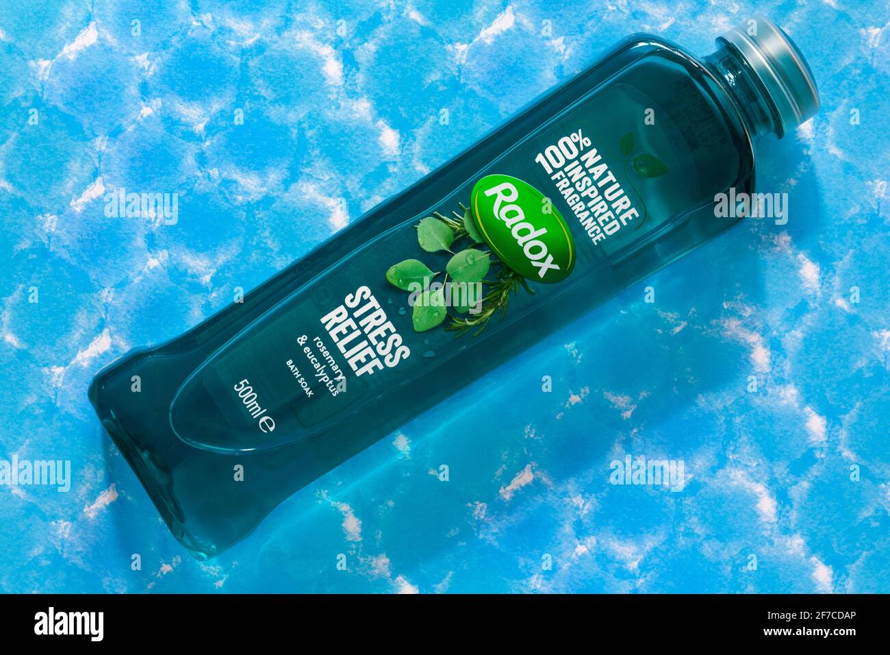 Bottiglia di bagno di rosmarino e eucalipto Radox stress Relief isolato su fondo a motivi blu - 100% di fragranza ispirata alla natura Foto Stock