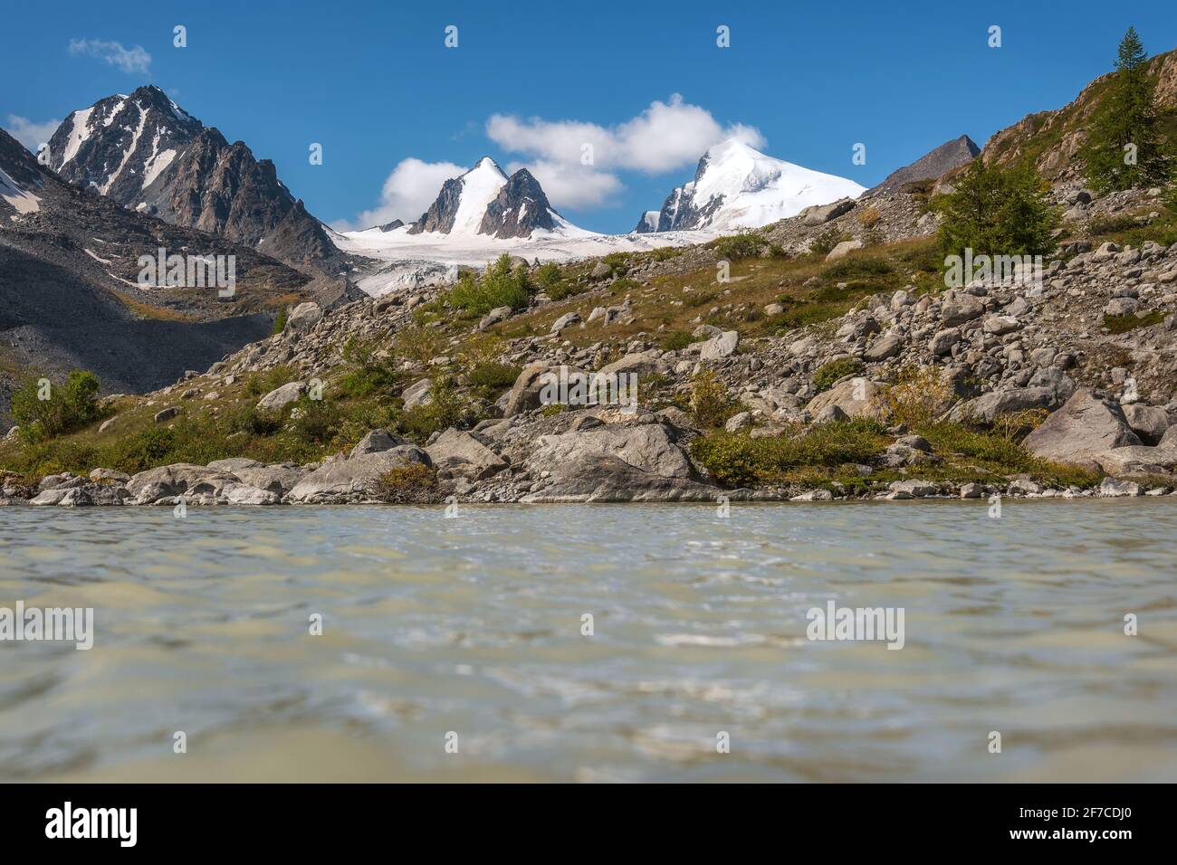 Bella vista estiva sul ghiacciaio da vicino, le cime delle montagne con neve, larici sul pendio e il lago sullo sfondo di una Foto Stock