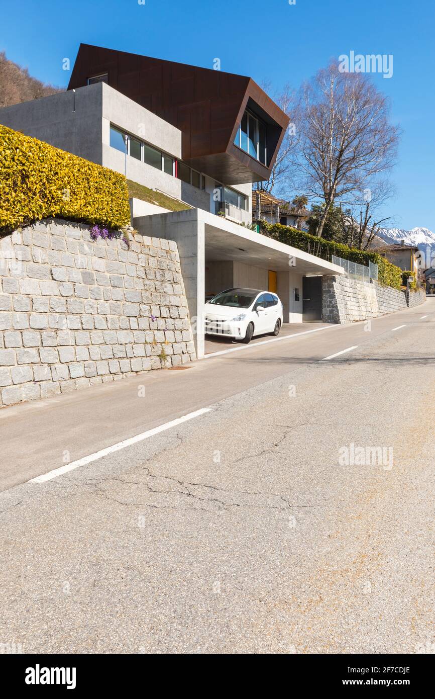 Esterno moderna villa isolata, circondata dalla natura. Rivestimenti in ferro e calcestruzzo. Strada anteriore deserta. Nessuno dentro Foto Stock